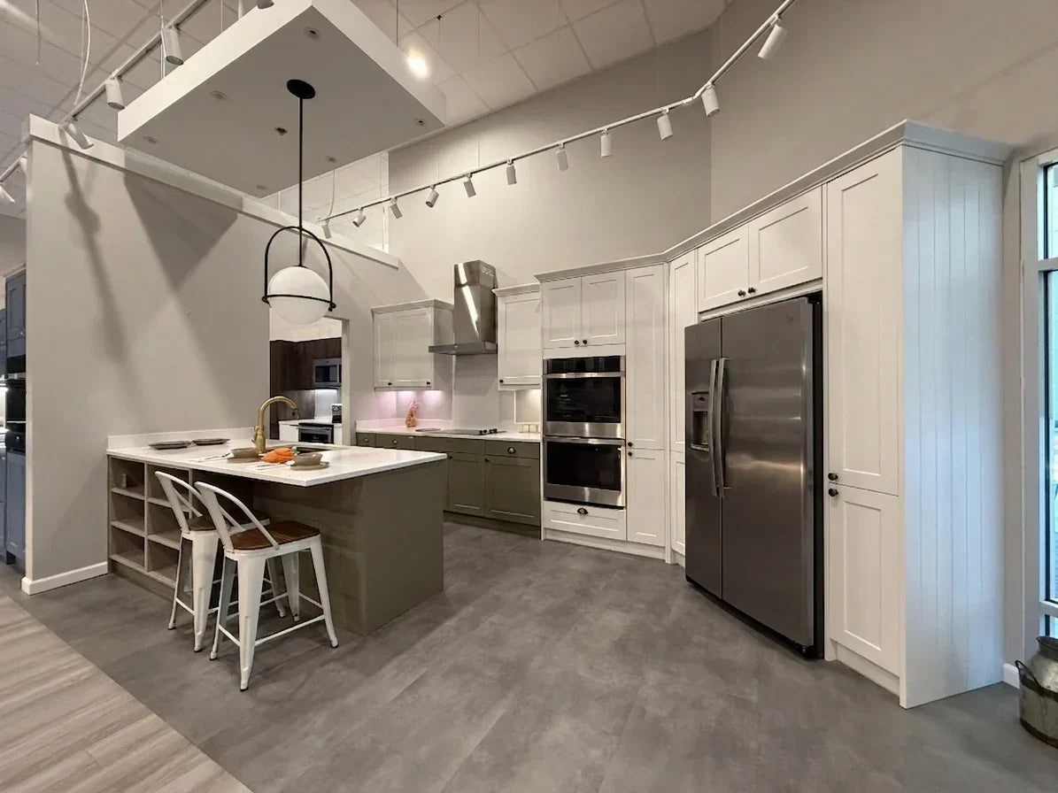 Wren Kitchens showroom display with white cabinetry, grey island and stainless steel appliances.