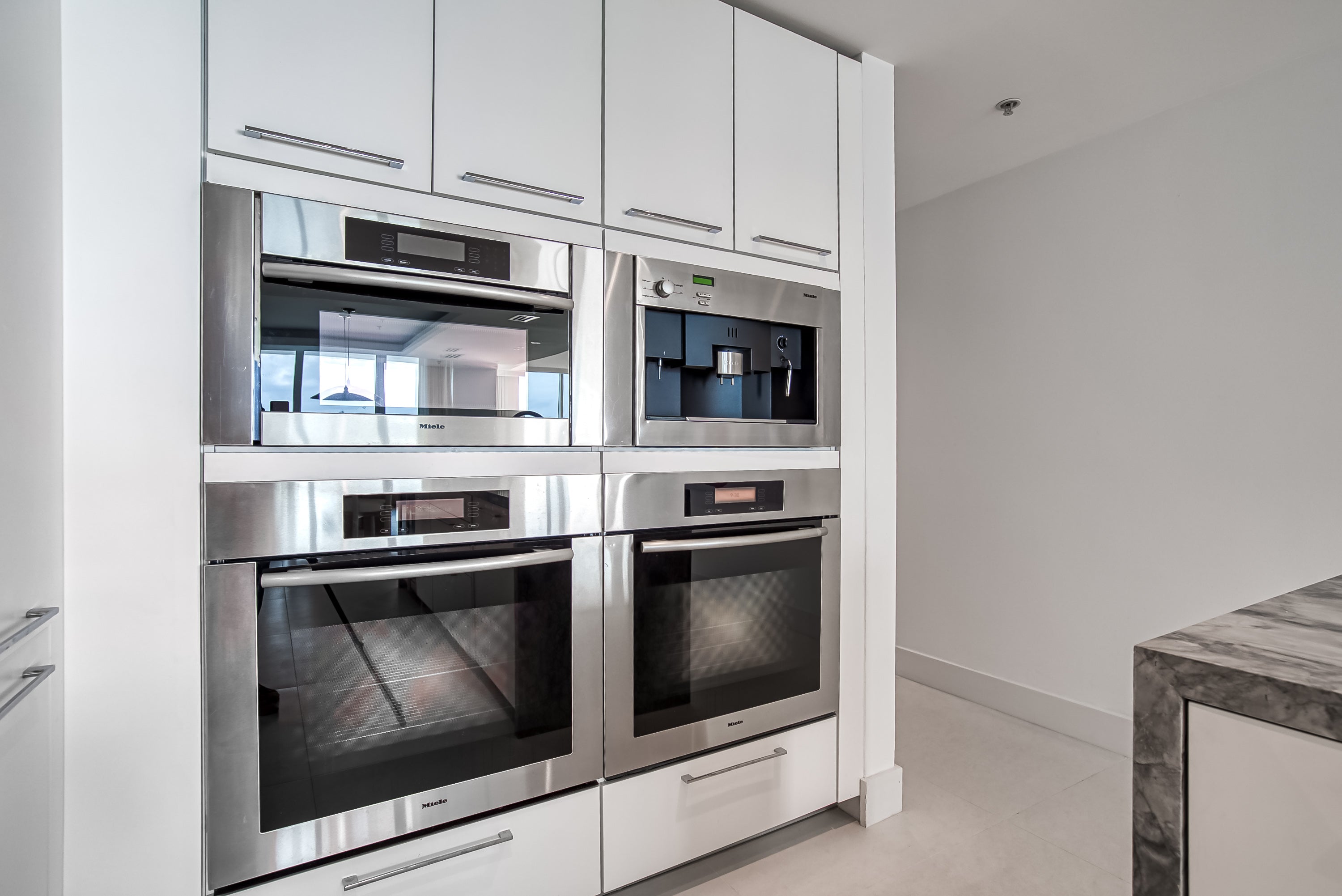 Poggenpohl White Modern Kitchen with Waterfall Island, Marble Countertops and Miele Appliances