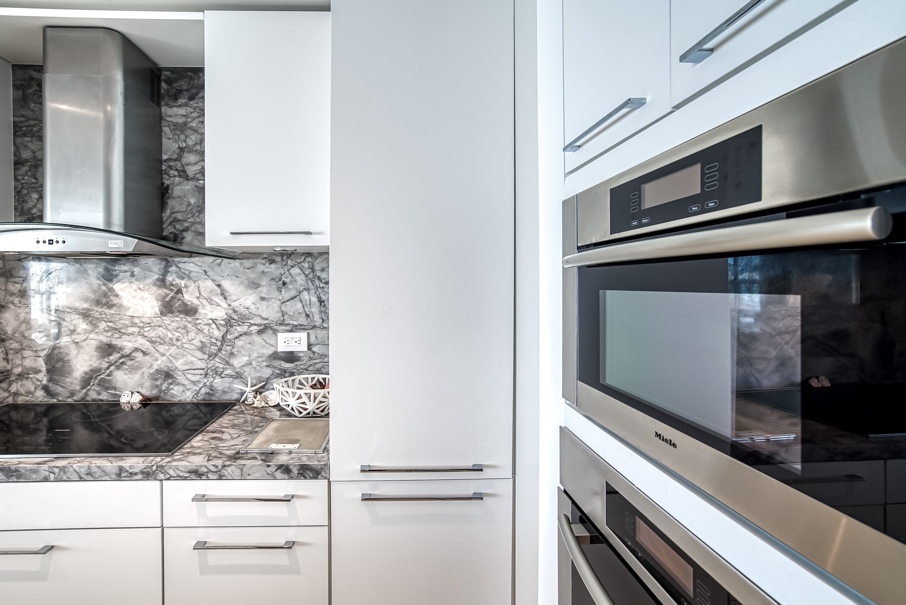 Poggenpohl White Modern Kitchen with Waterfall Island, Marble Countertops and Miele Appliances