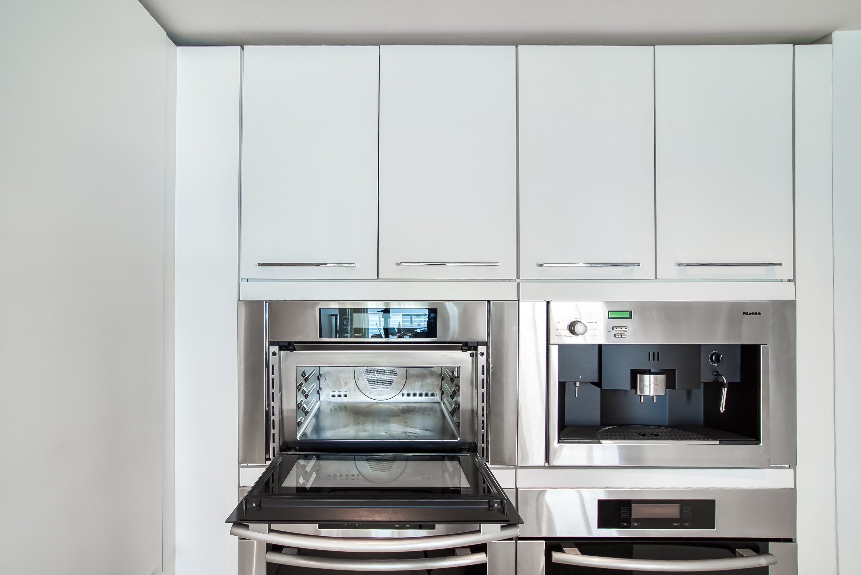 Poggenpohl White Modern Kitchen with Waterfall Island, Marble Countertops and Miele Appliances