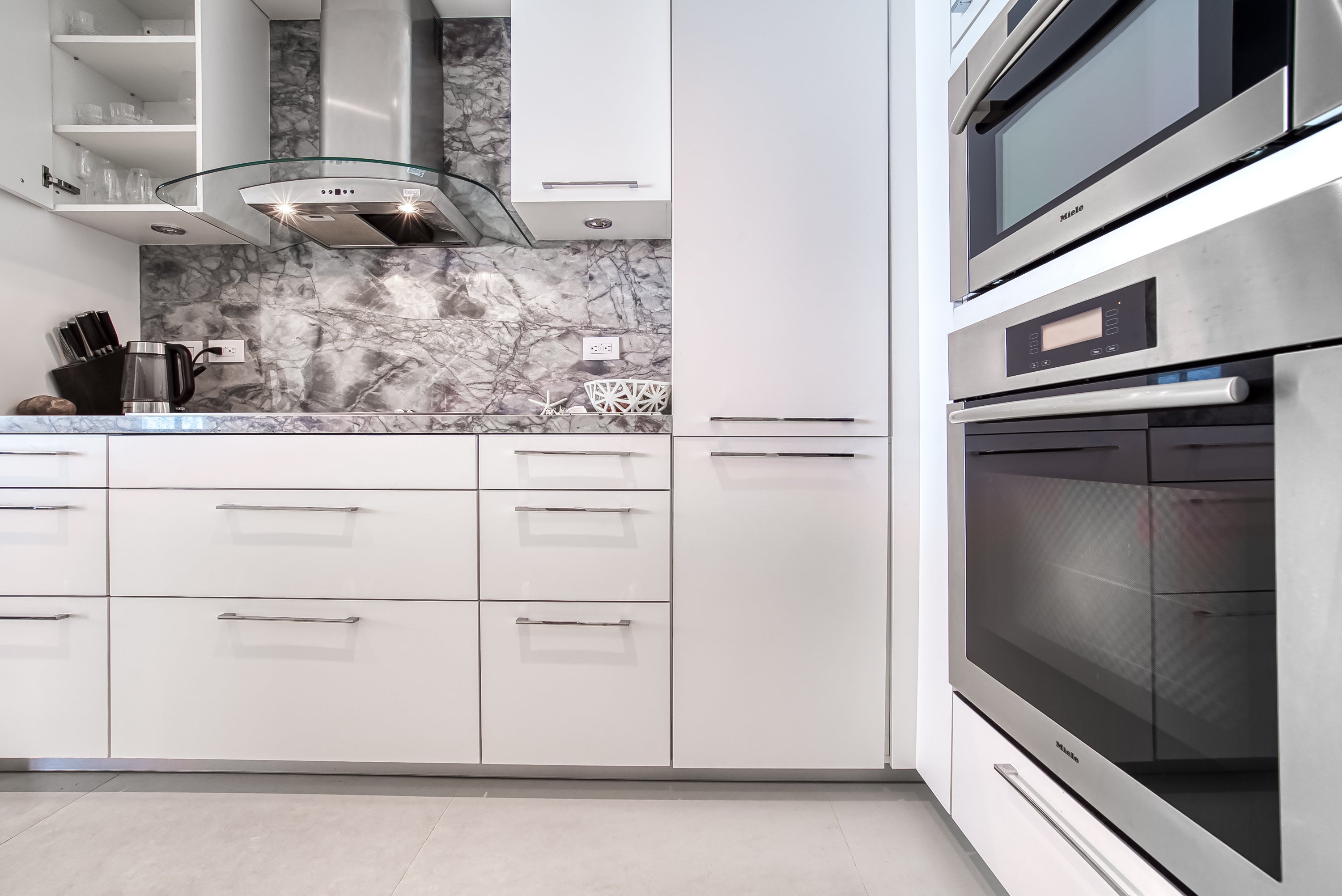 Poggenpohl White Modern Kitchen with Waterfall Island, Marble Countertops and Miele Appliances