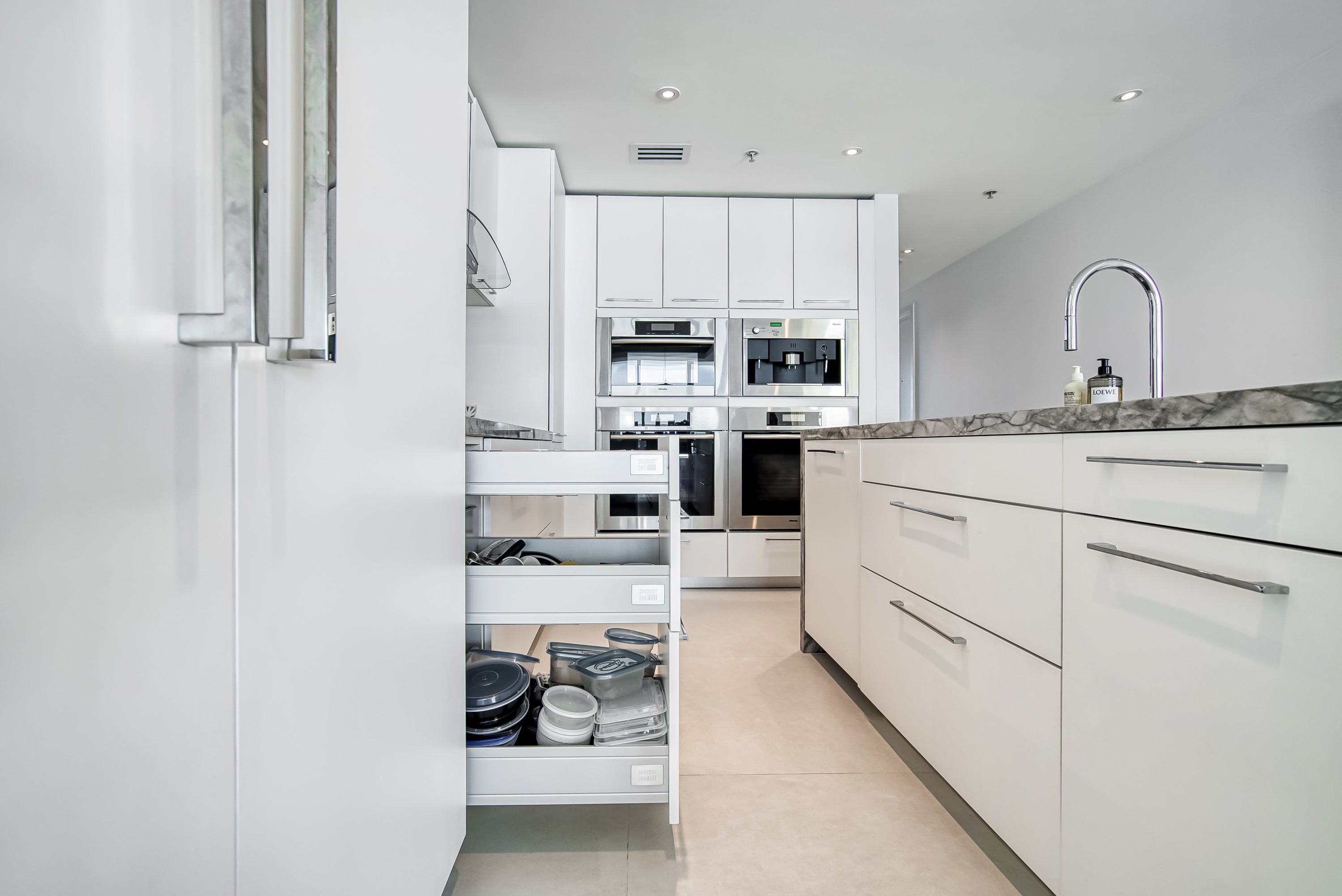 Poggenpohl White Modern Kitchen with Waterfall Island, Marble Countertops and Miele Appliances