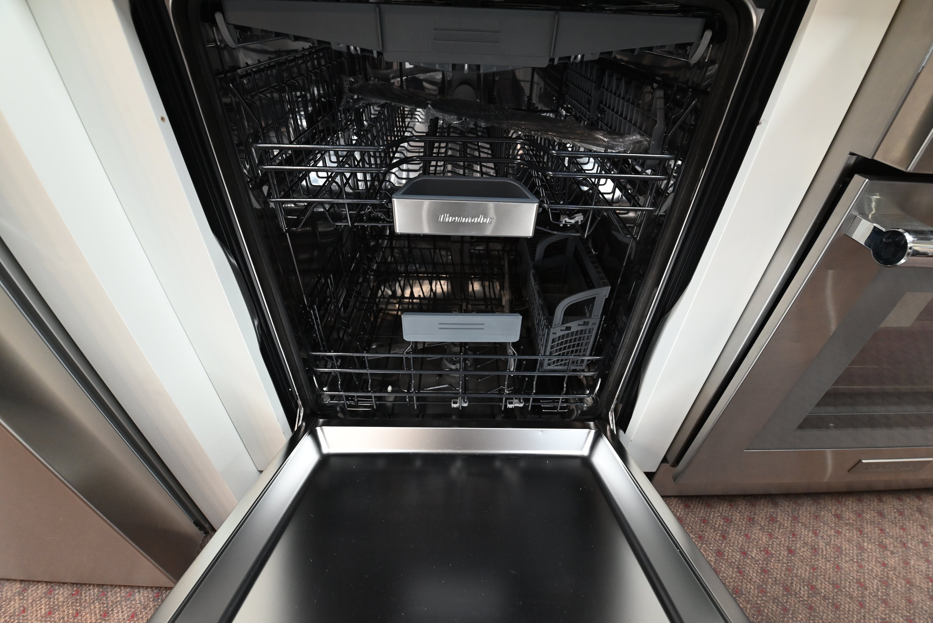Luxury 24 inch integrated dishwasher open showing full stainless steel tub and 3 loading racks