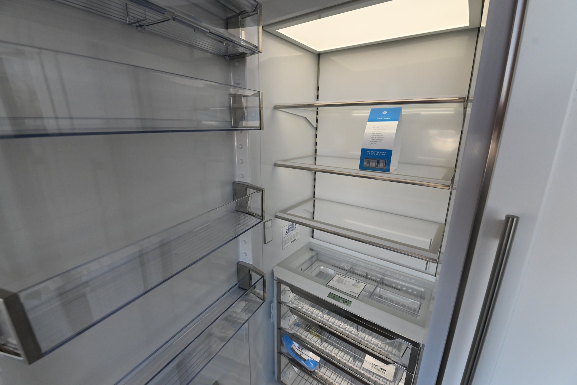 Sub Zero 30 inch refrigerator column showing open door glass shelving crisper drawers and LED lights