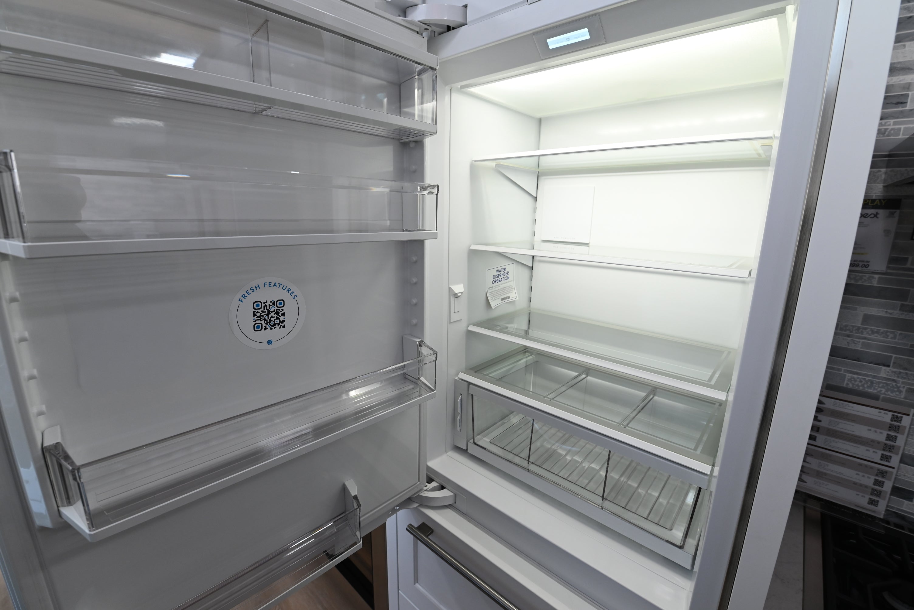 Luxury 30 inch integrated refrigerator showing open doors holding fresh food and internal water dispenser