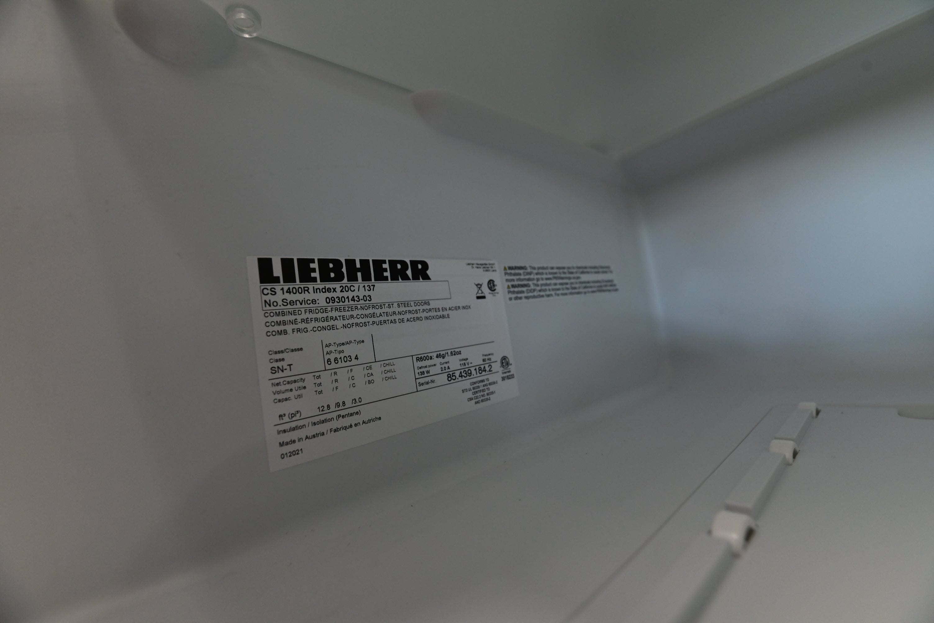A close-up shot inside the white interior of a Liebherr CS 1440R Index GGC (1) refrigerator, showing the product's technical specification label on the wall.