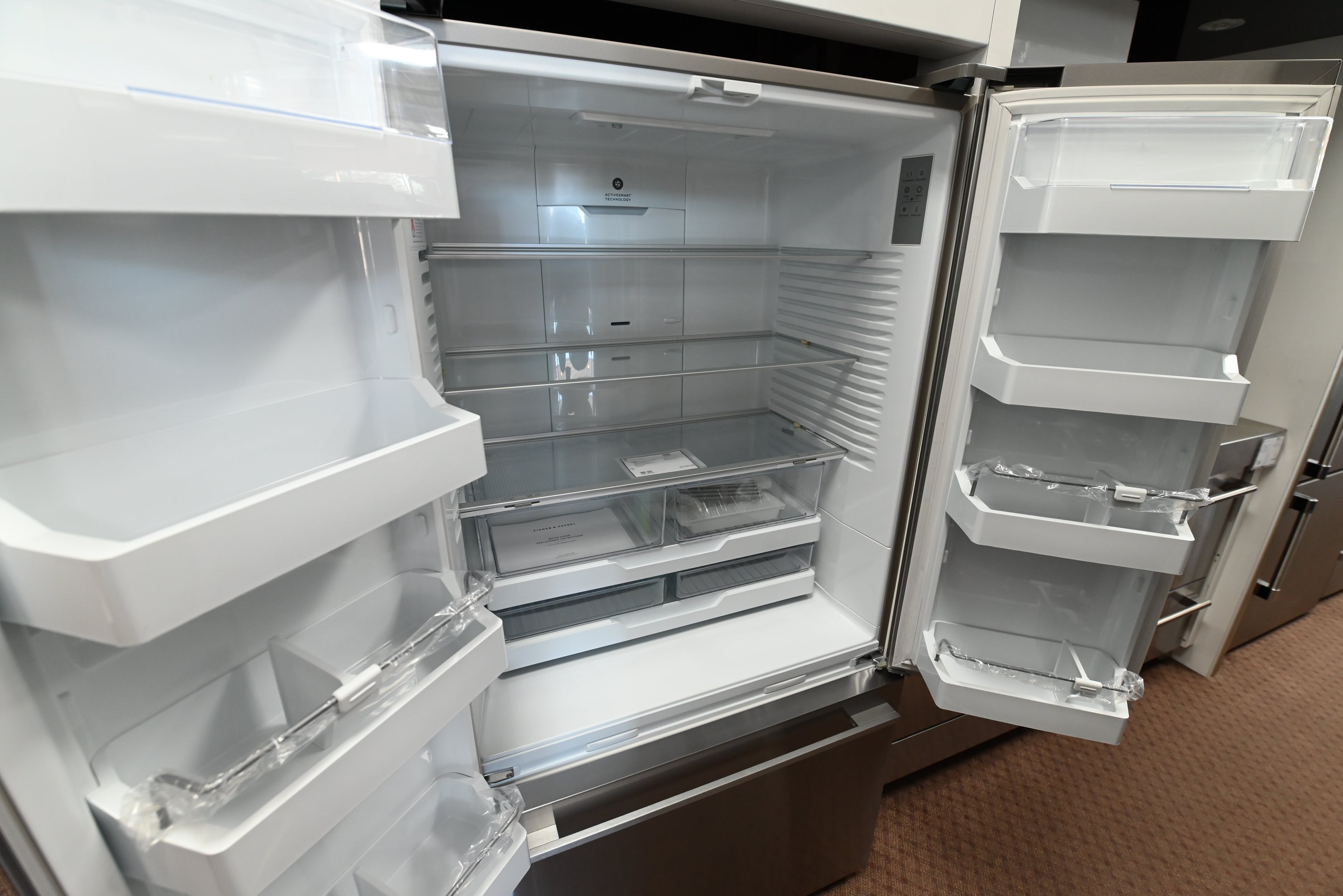 Open fresh food compartment view of the Fisher Paykel 20.1 cu ft refrigerator showing glass shelves and LED lighting