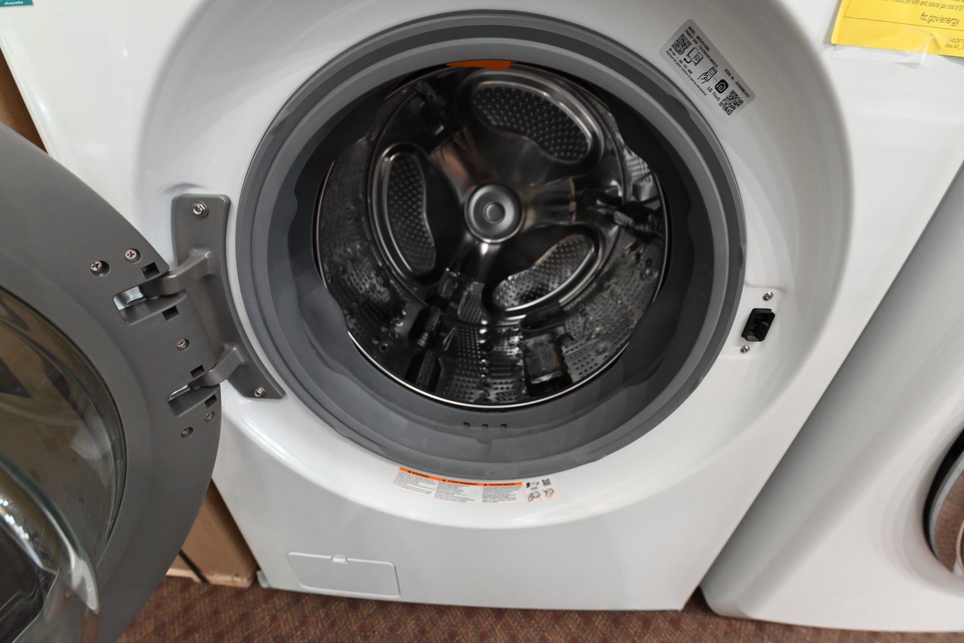 LG white gas WashTower with black tinted tempered glass doors open showing interior steel drums