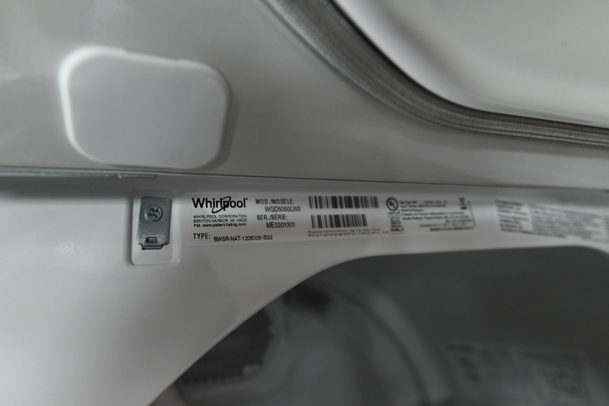 Close-up of a white Whirlpool appliance interior showing a product label sticker with barcode and model information.
