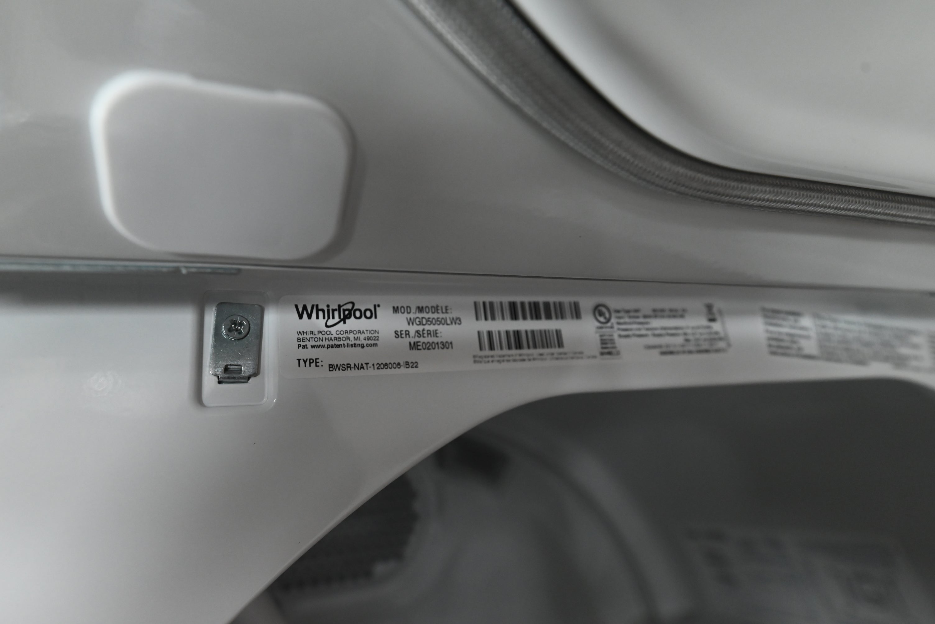 Close-up of a white Whirlpool appliance interior showing a product label sticker with barcode and model information.