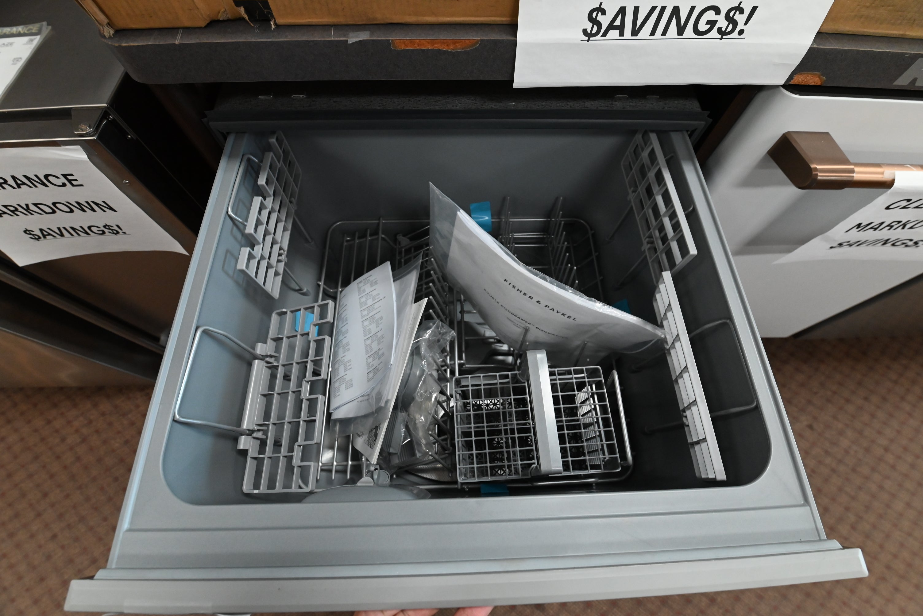 Close up view of the top drawer open on a Fisher and Paykel dishwasher showing adjustable racks and cup shelves