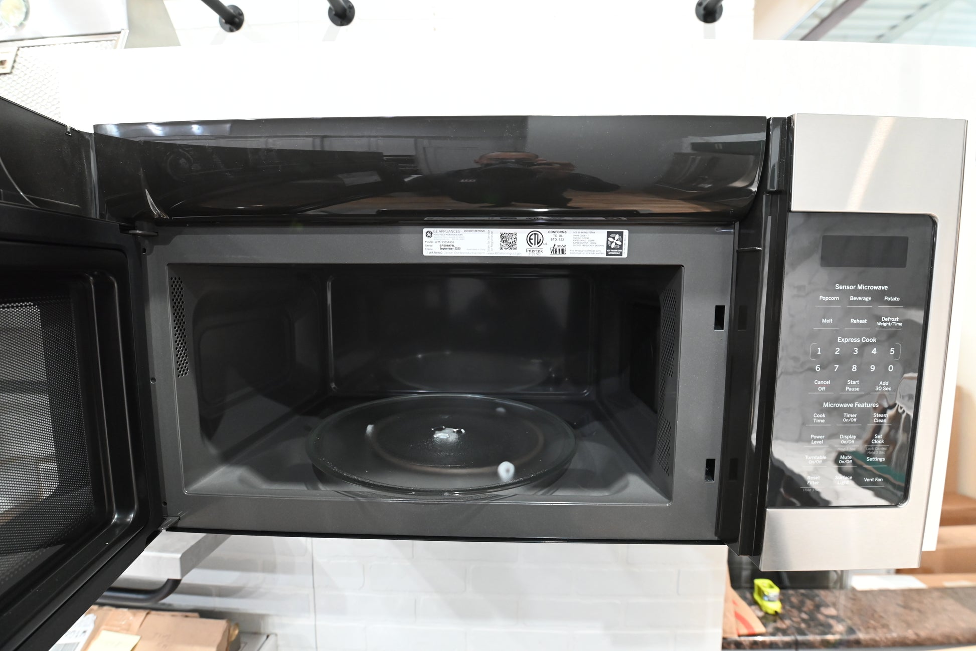 Open door view of a GE JVM7195SKSS microwave showing the large grey interior and rotating glass turntable