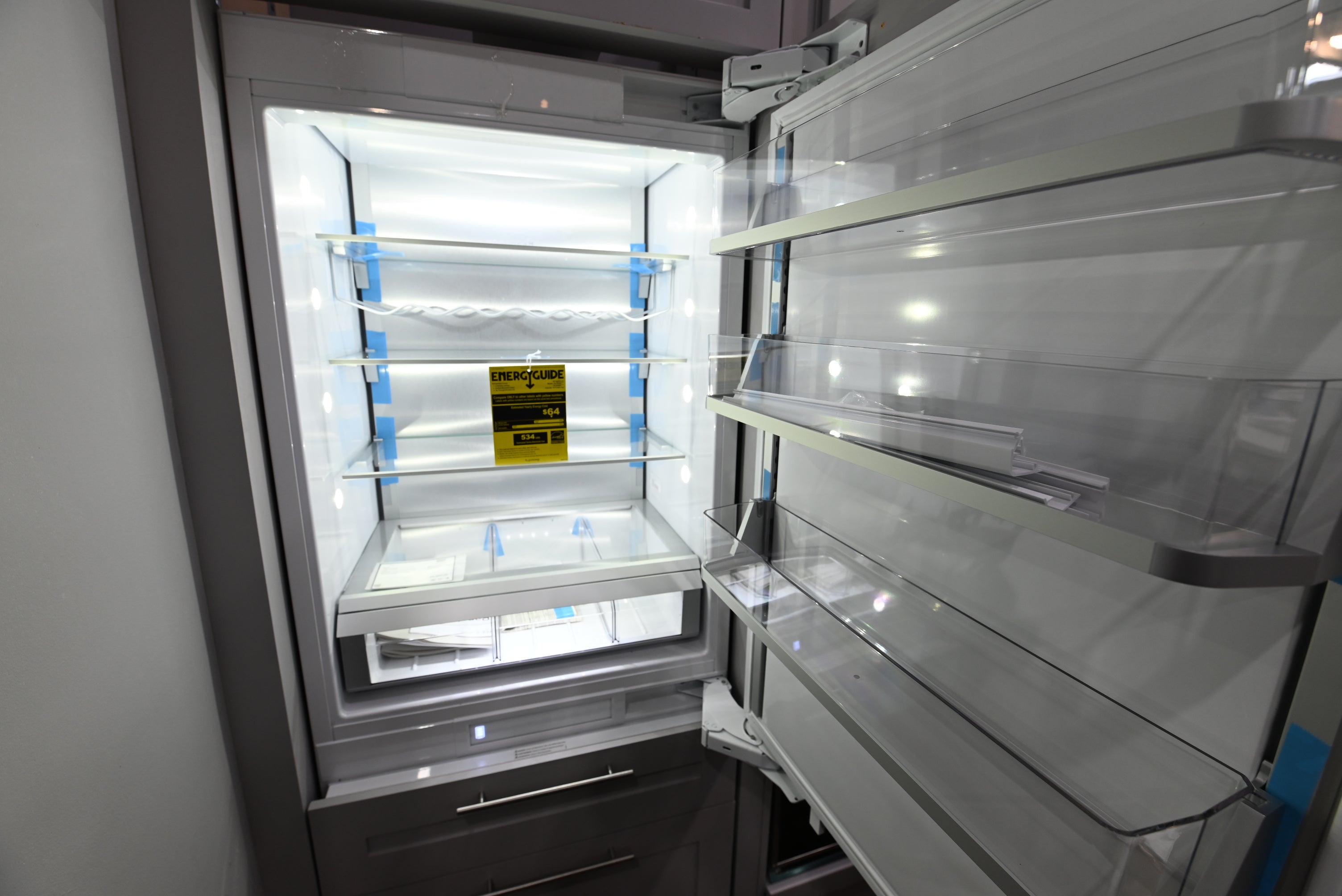 Interior view of the illuminated glass shelving and dual evaporator storage zones of a Monogram ZIC303NPPII integrated refrigerator