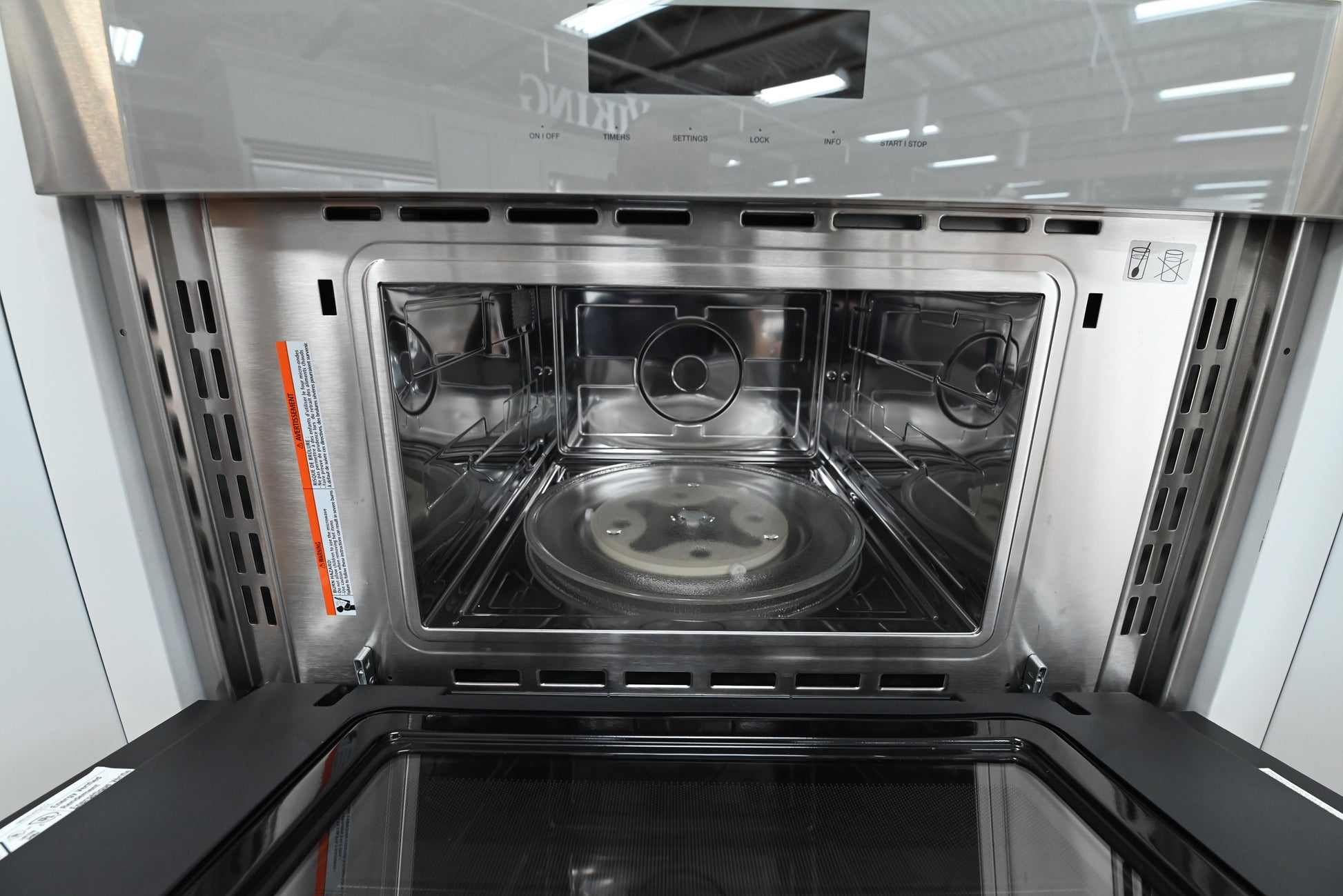 Luxury 30 inch combo wall oven open showing upper microwave cavity with turntable and lower convection cavity with telescopic rack