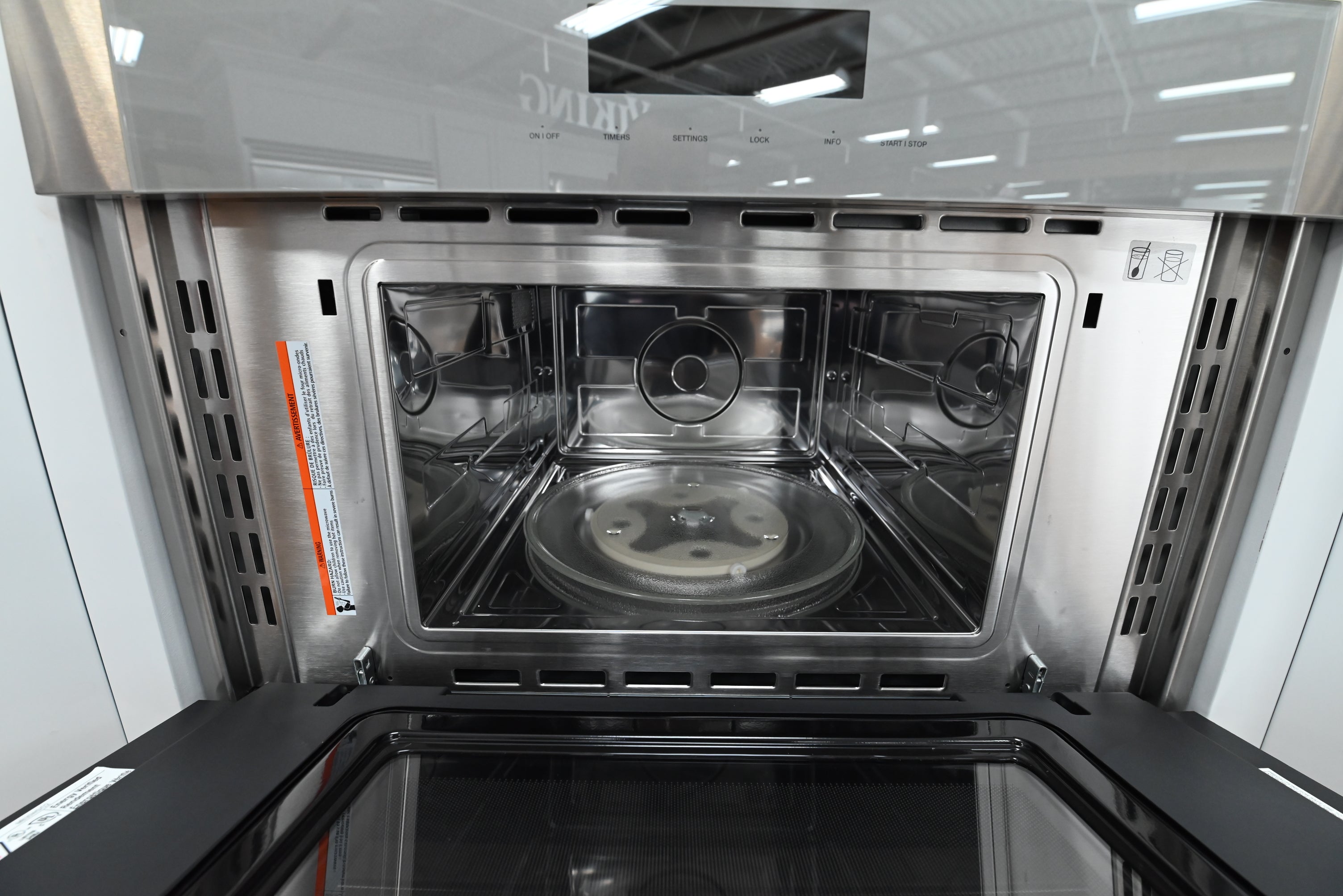 Luxury 30 inch combo wall oven open showing upper microwave cavity with turntable and lower convection cavity with telescopic rack
