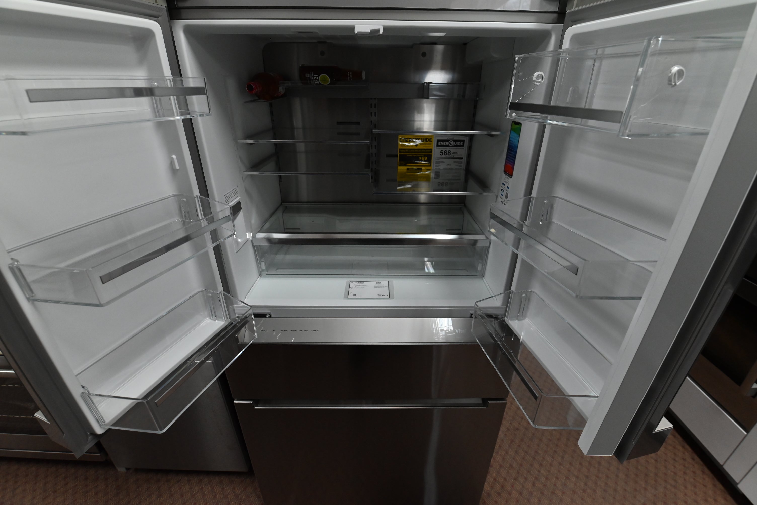 Luxury 4 door freestanding refrigerator open showing stainless steel backwall and FlexBar shelf