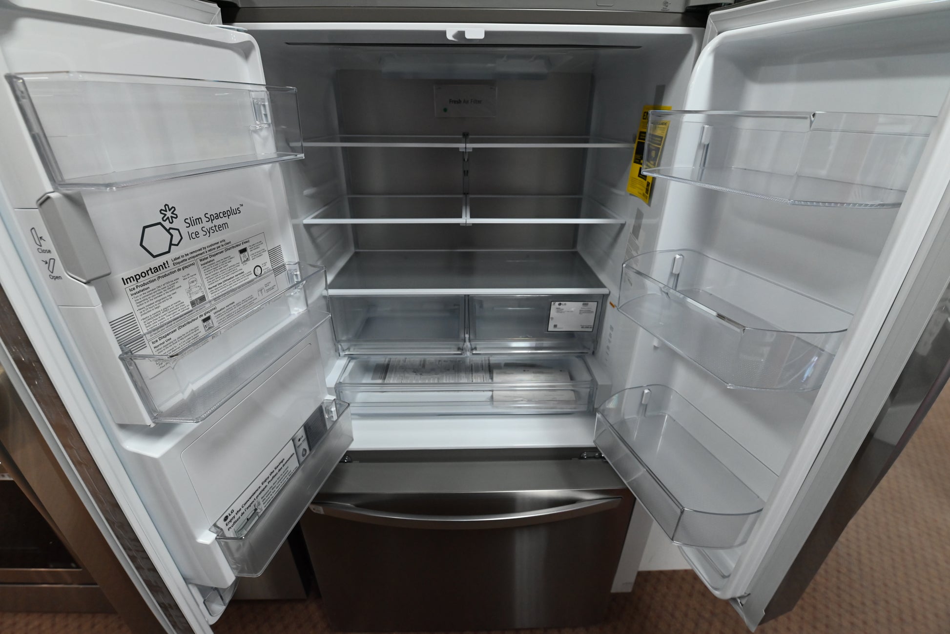 Interior view of the illuminated open shelving and Cool Guard metal back wall panel inside the LG LRFXC2606S refrigerator