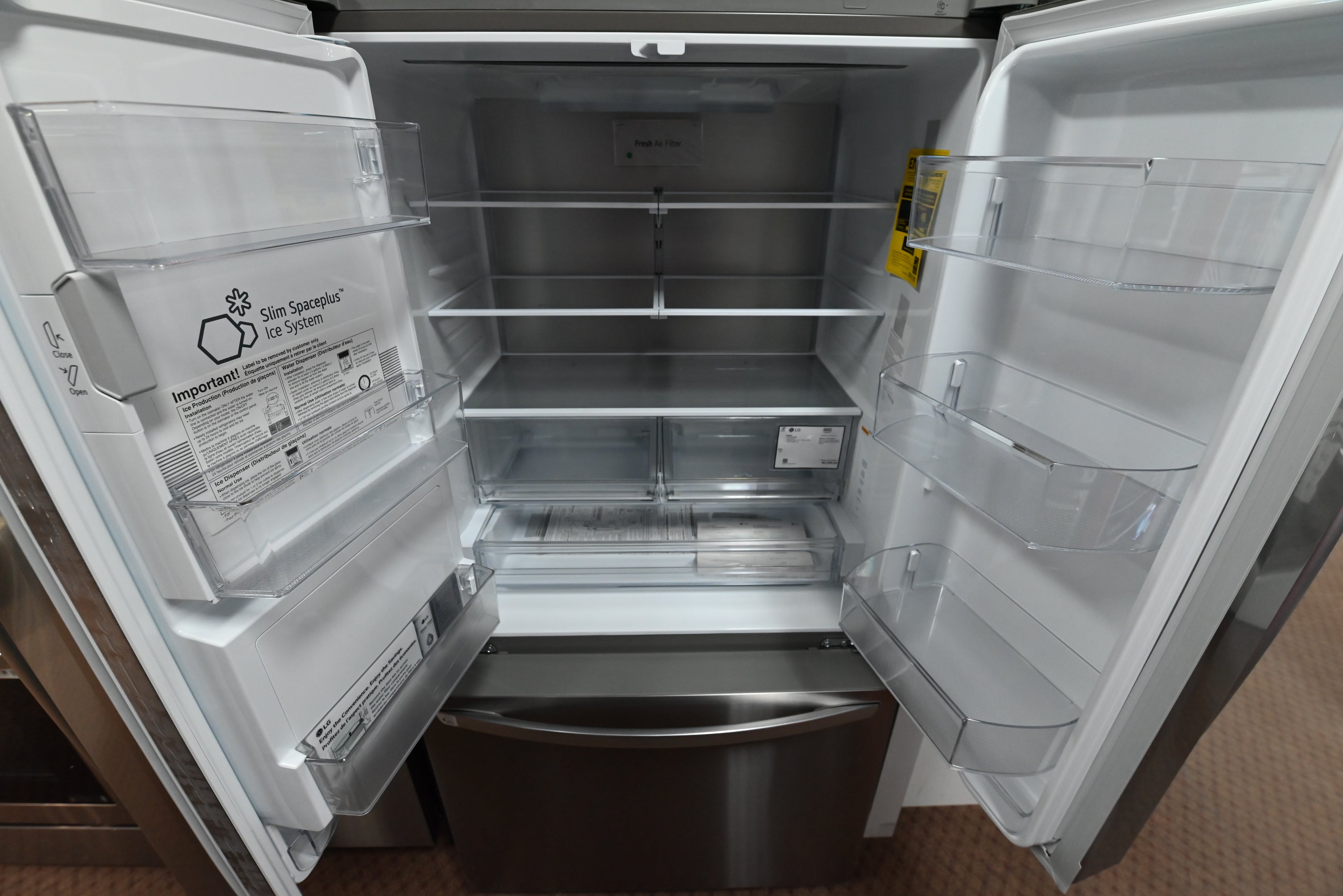 Interior view of the illuminated open shelving and Cool Guard metal back wall panel inside the LG LRFXC2606S refrigerator