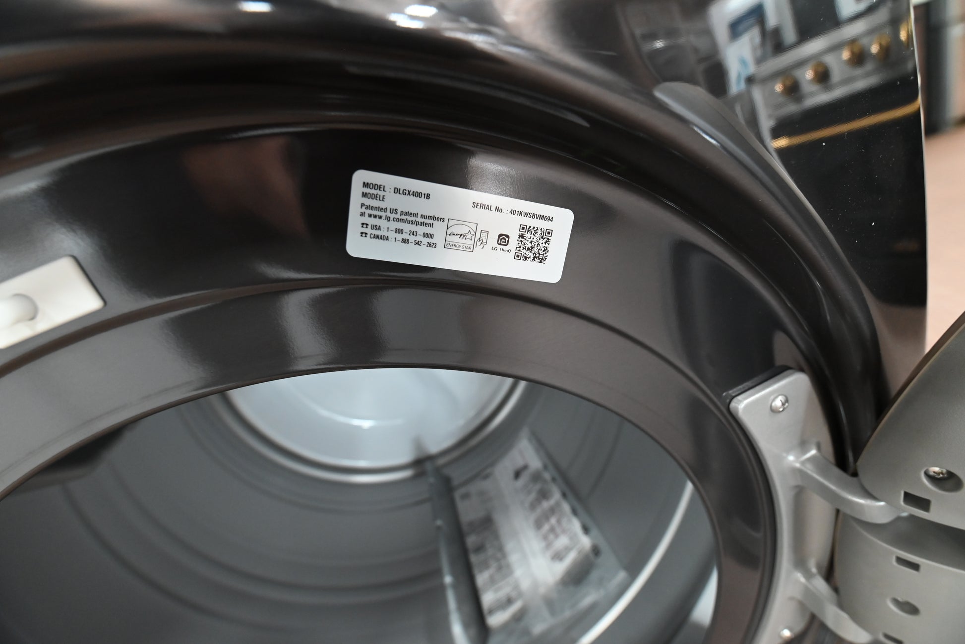 Close-up of a dark gray washing machine door frame with a white product label sticker inside the open door.