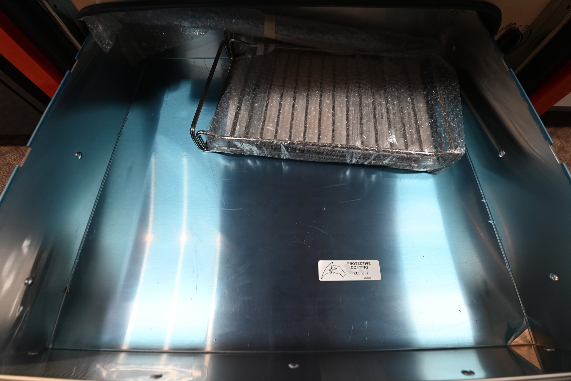 Open drawer view of a KitchenAid KOWT100ESS warming drawer showing the concealed top control dials and steel liner