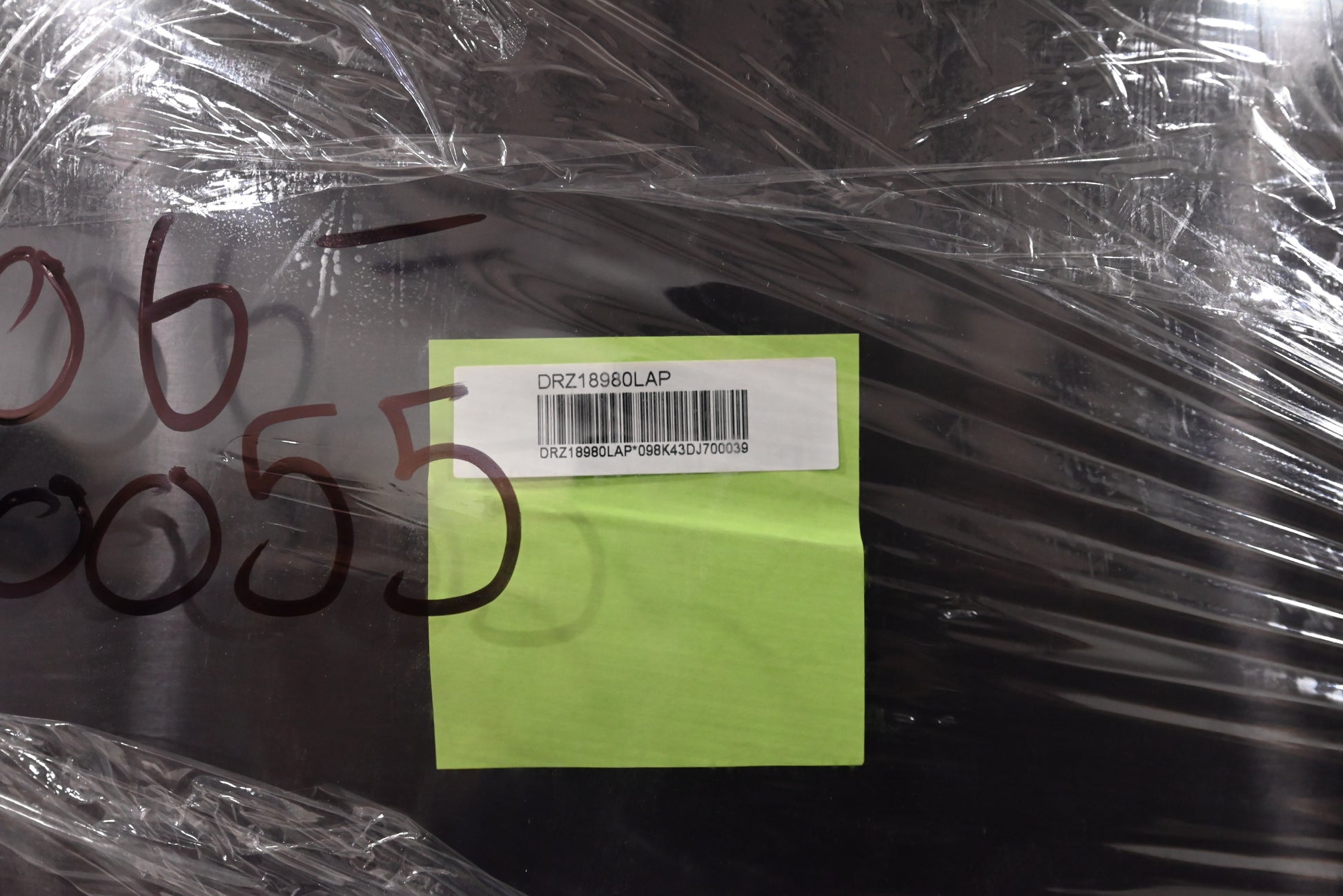 Product wrapped in clear plastic with a green label and numbers on a dark surface