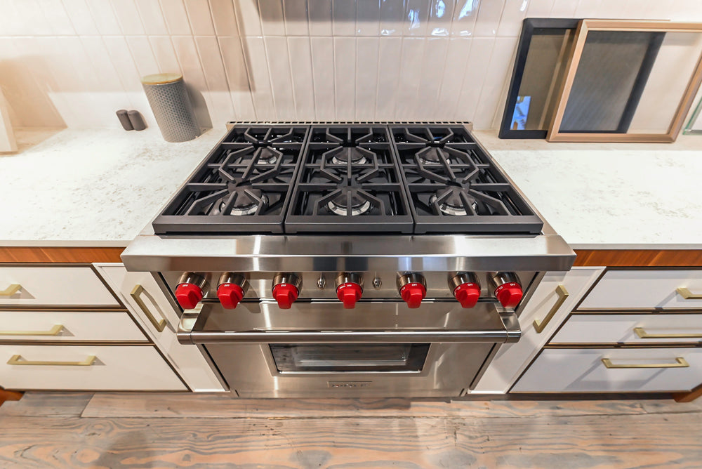 Luxury 36 inch Wolf gas range cooktop showing six dual stacked sealed burners and continuous cast iron grates