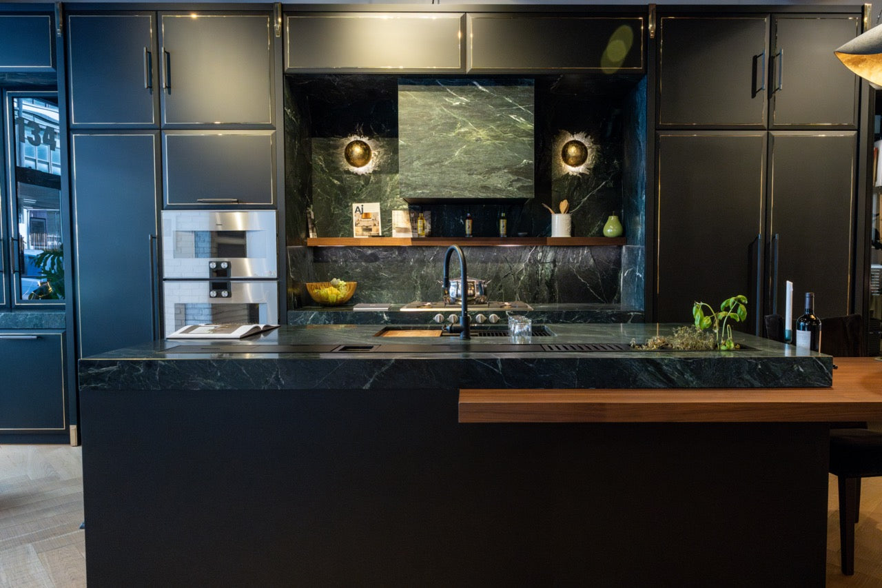 Close up view of the seamless handleless black cabinet doors and thick Nero Assoluto solid stone countertop on a luxury kitchen island