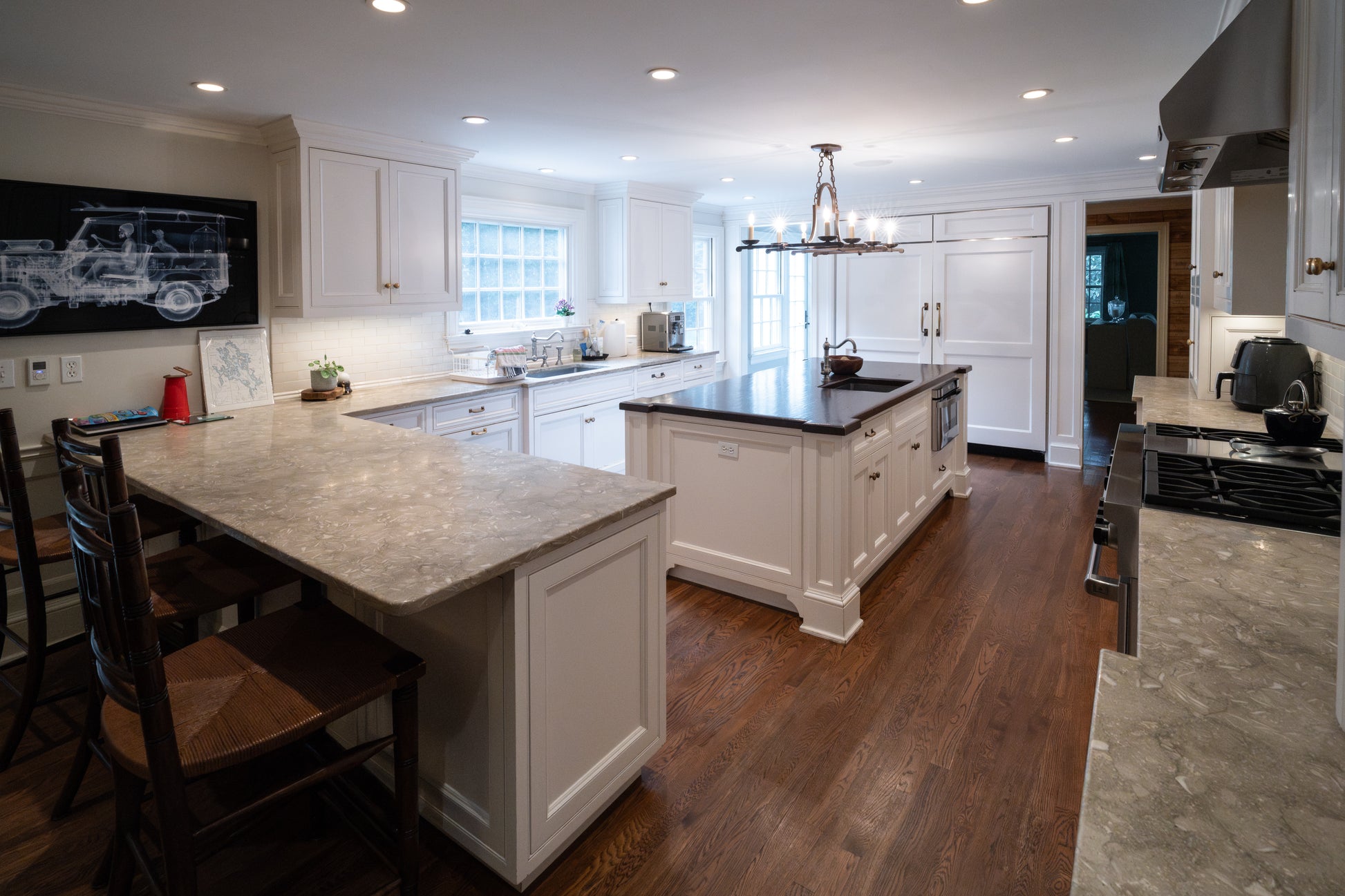 The Montclair transitional white kitchen package featuring custom shaker cabinetry a large central island and a 48 inch Wolf range