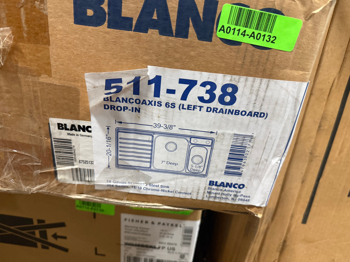 A close-up of a cardboard shipping box with a white product label for a Blanco 511-738 Blancoaxis 6S (left drainboard) drop-in sink. The label features a blue line drawing of a double basin sink with dimensions and the Blanco brand name.