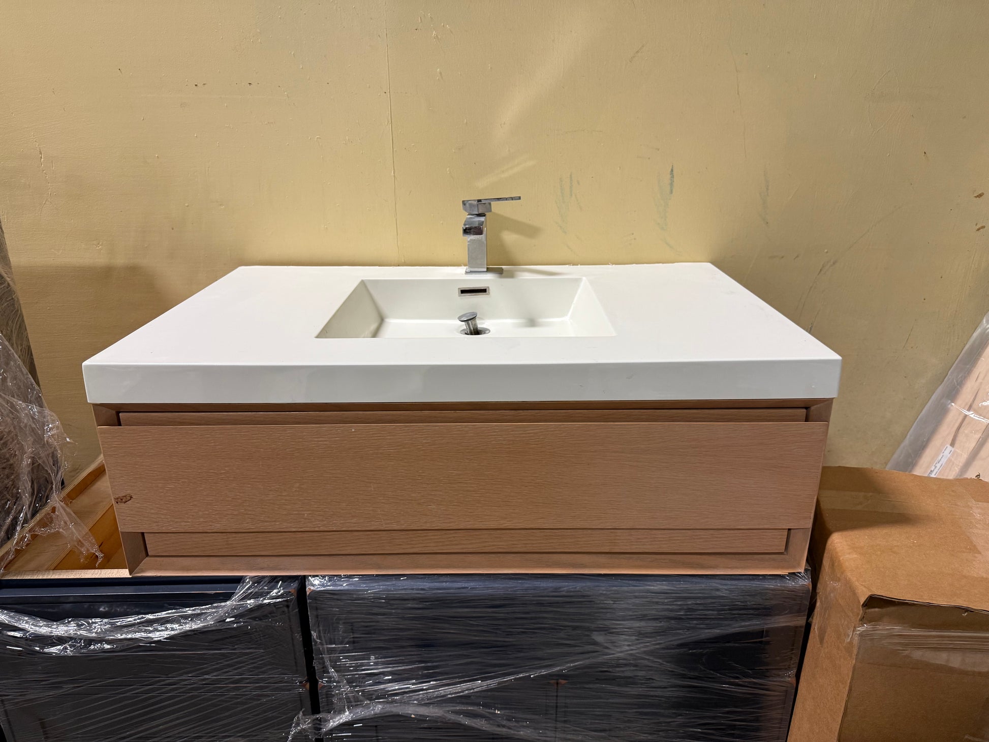 Close up view of the light oak wood grain drawers and solid surface sink top on a 36 inch wall mount vanity