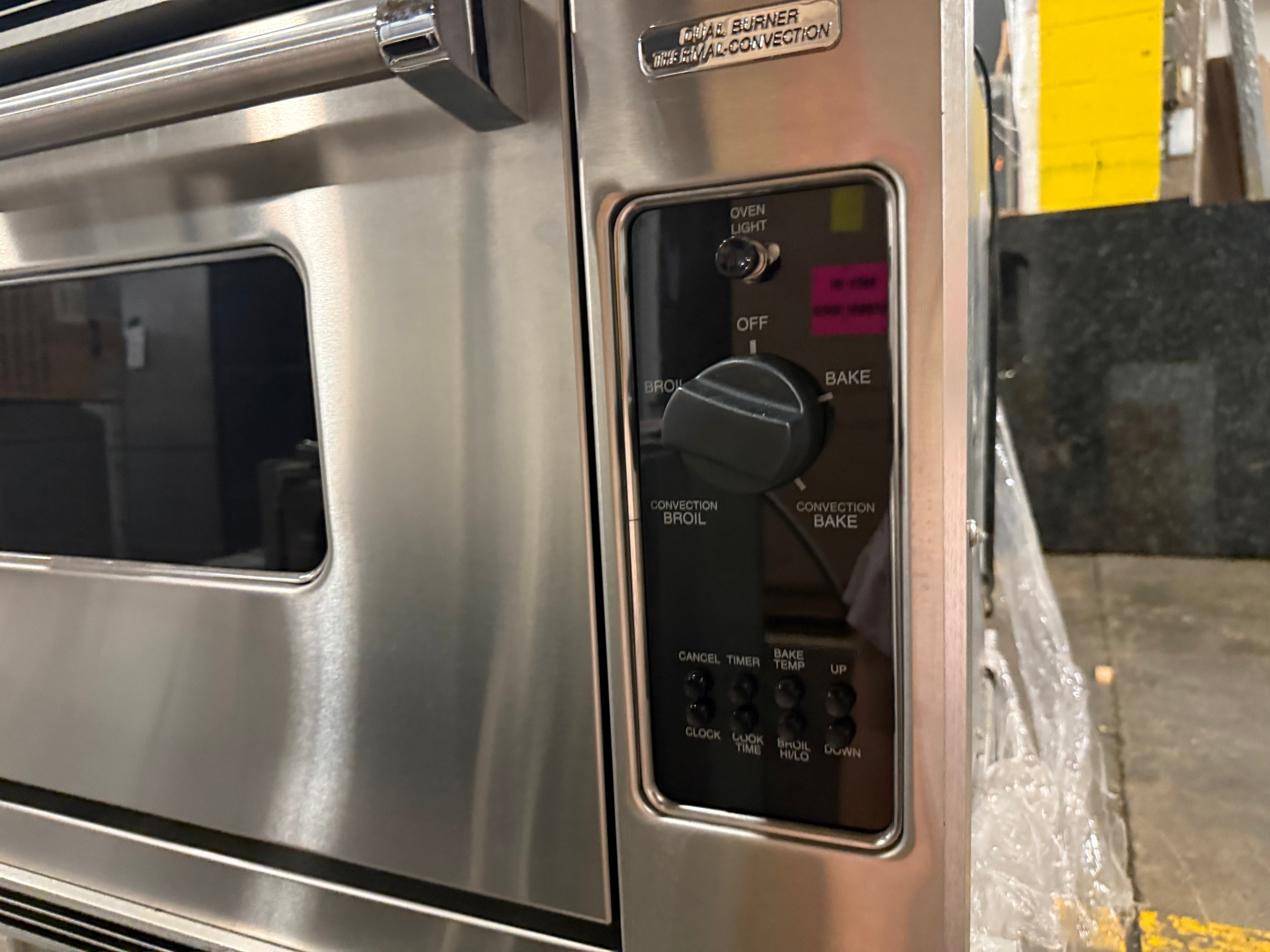 Close-up of a stainless steel commercial oven control panel with a black dial and buttons, including Bake, Convection Bake, Broil, and Burner settings.
