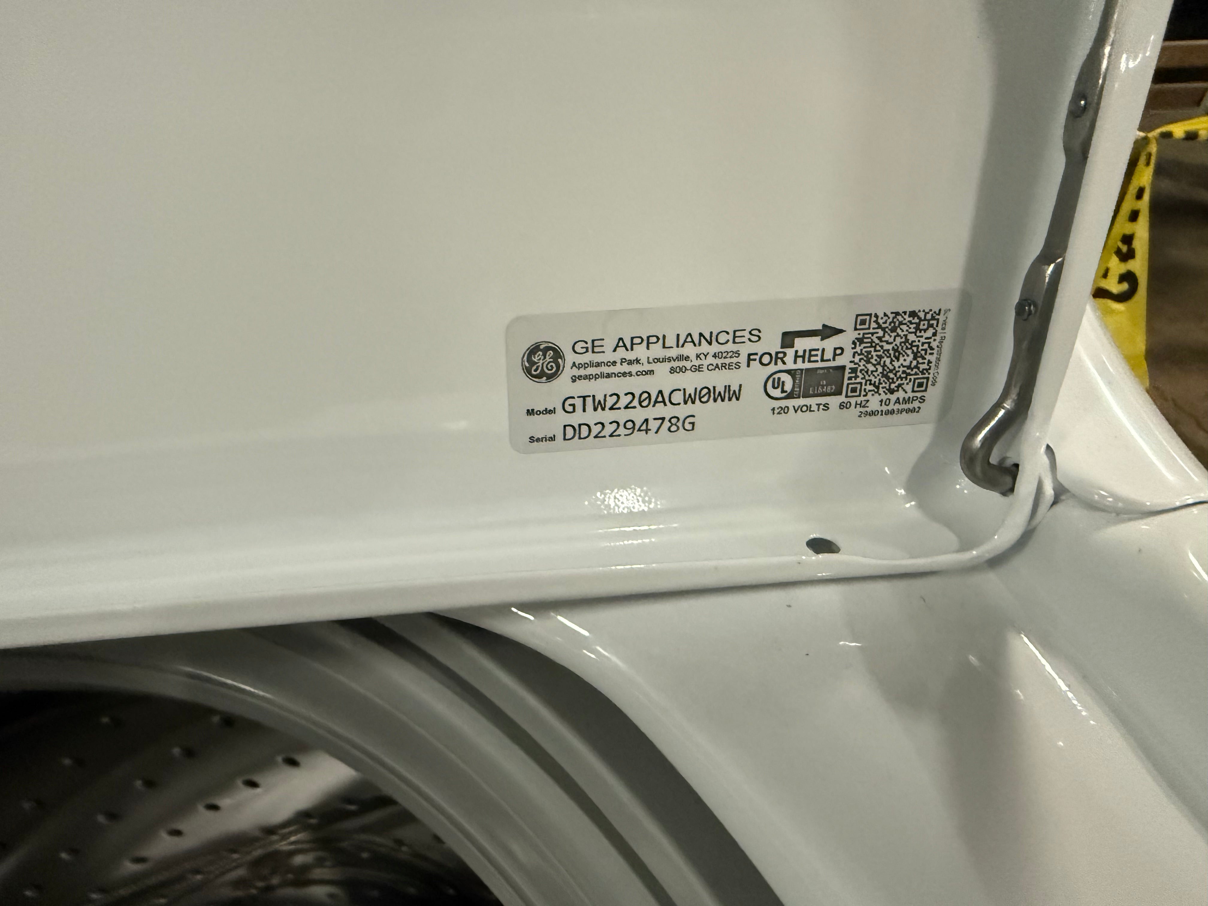 A close-up of a white GE Appliances appliance interior showing a product label with model GTW22ACW0WW and a QR code.