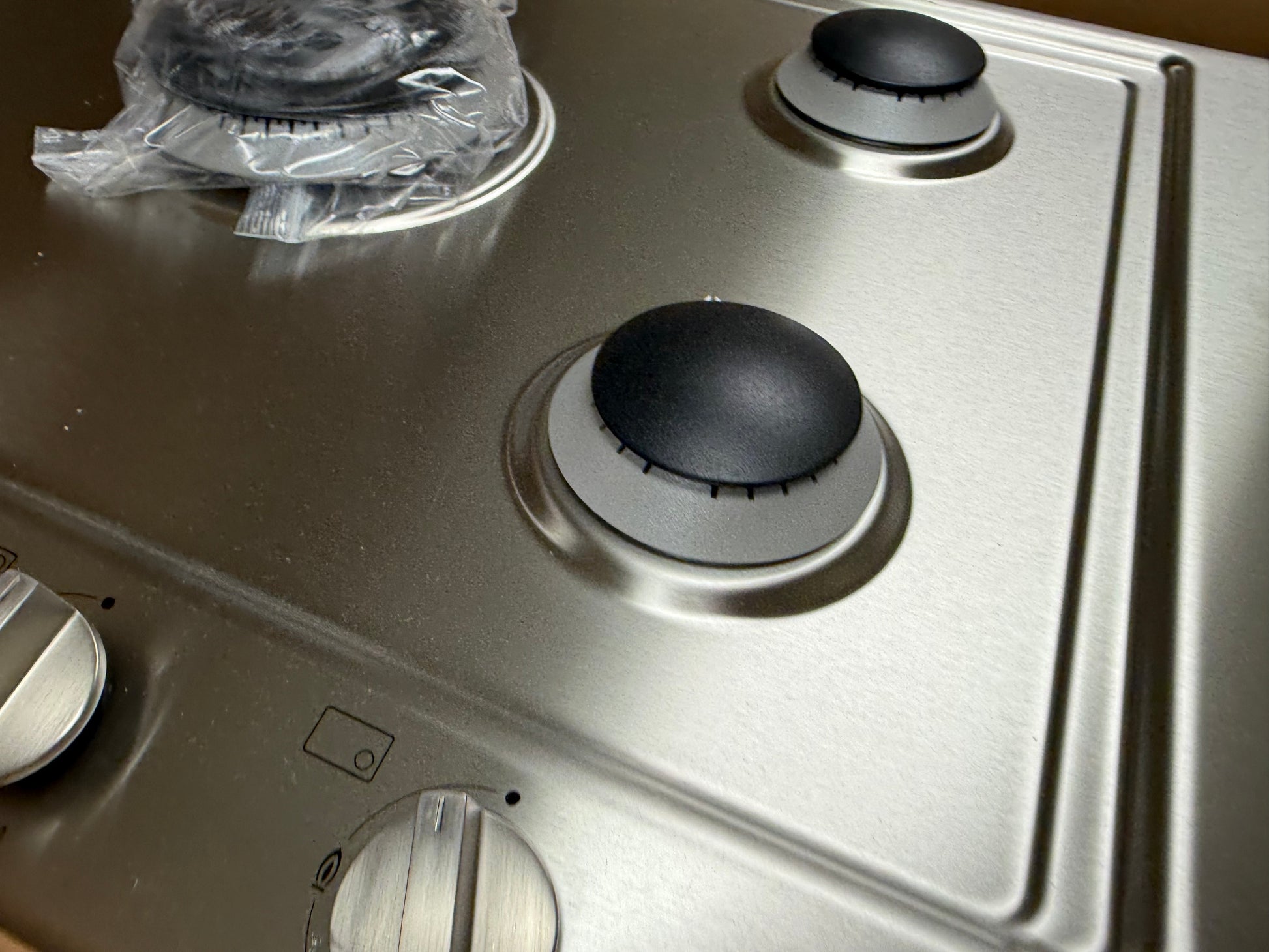 Close up of center 15300 BTU dual wok burner and metal knobs on Miele KM2032G cooktop