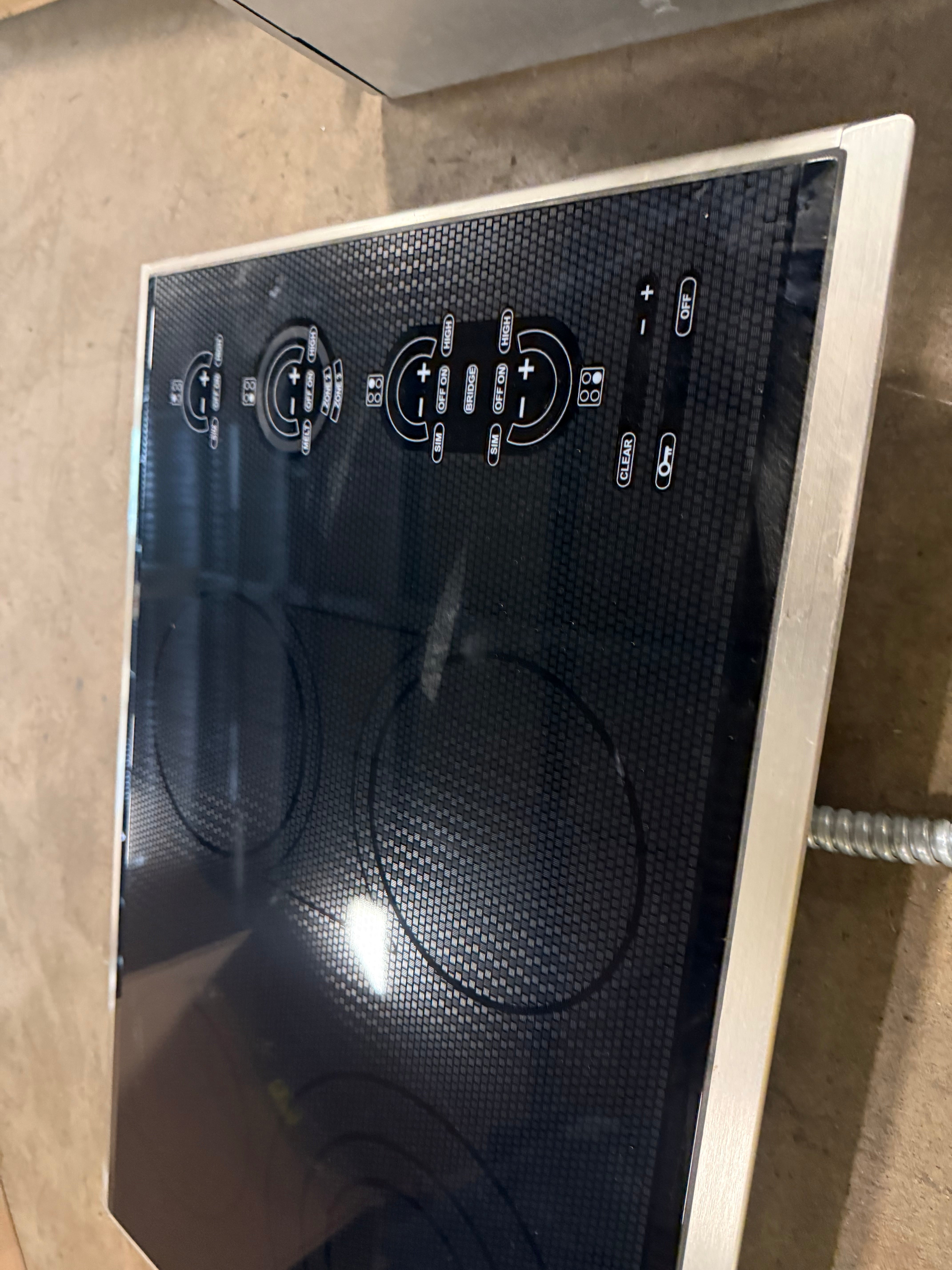 Close up of digital touch controls and triple zone heating element on Wolf 30 electric cooktop