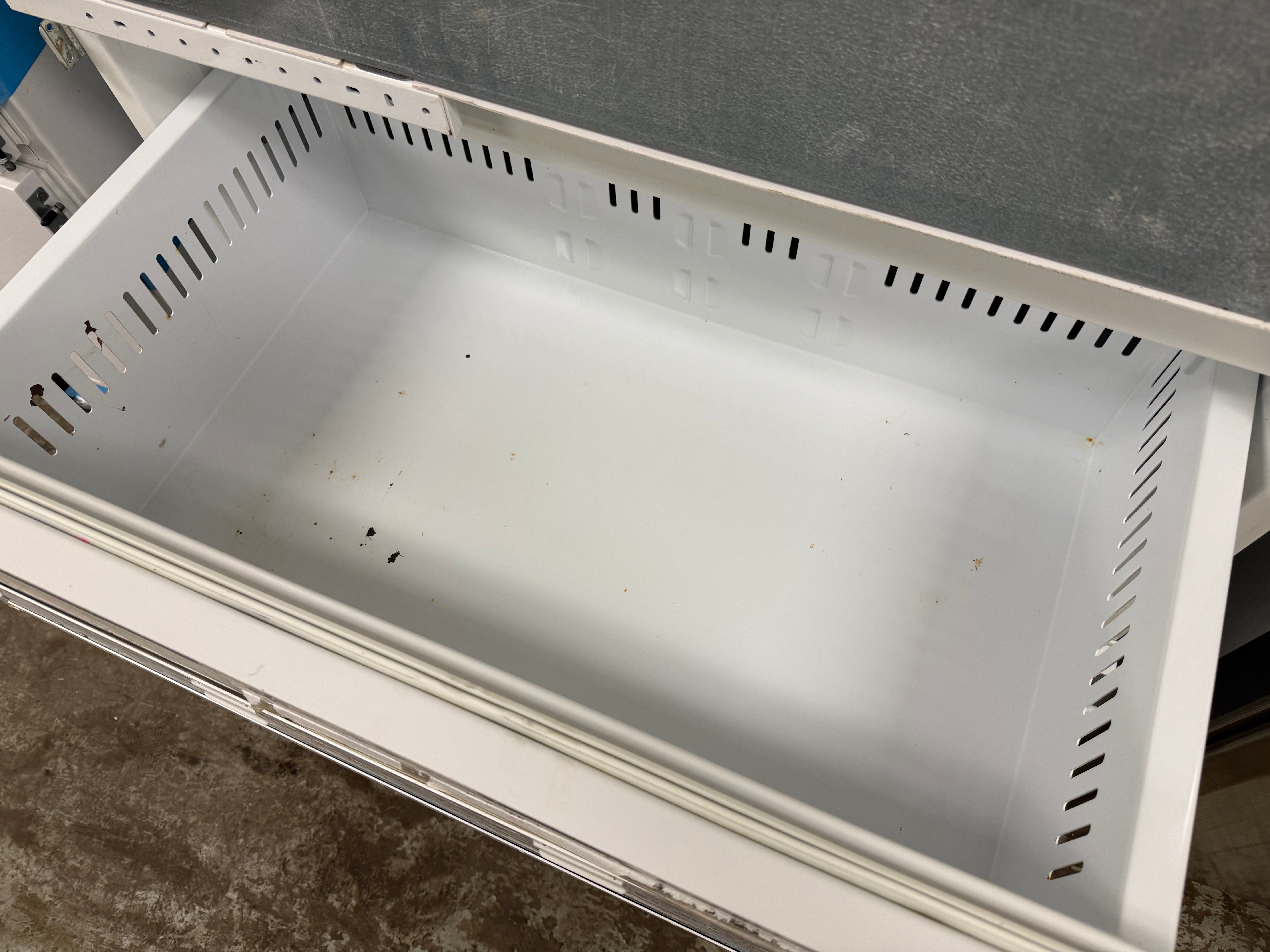 A white plastic drawer organizer insert with ventilation slots, shown pulled out of a white drawer unit.