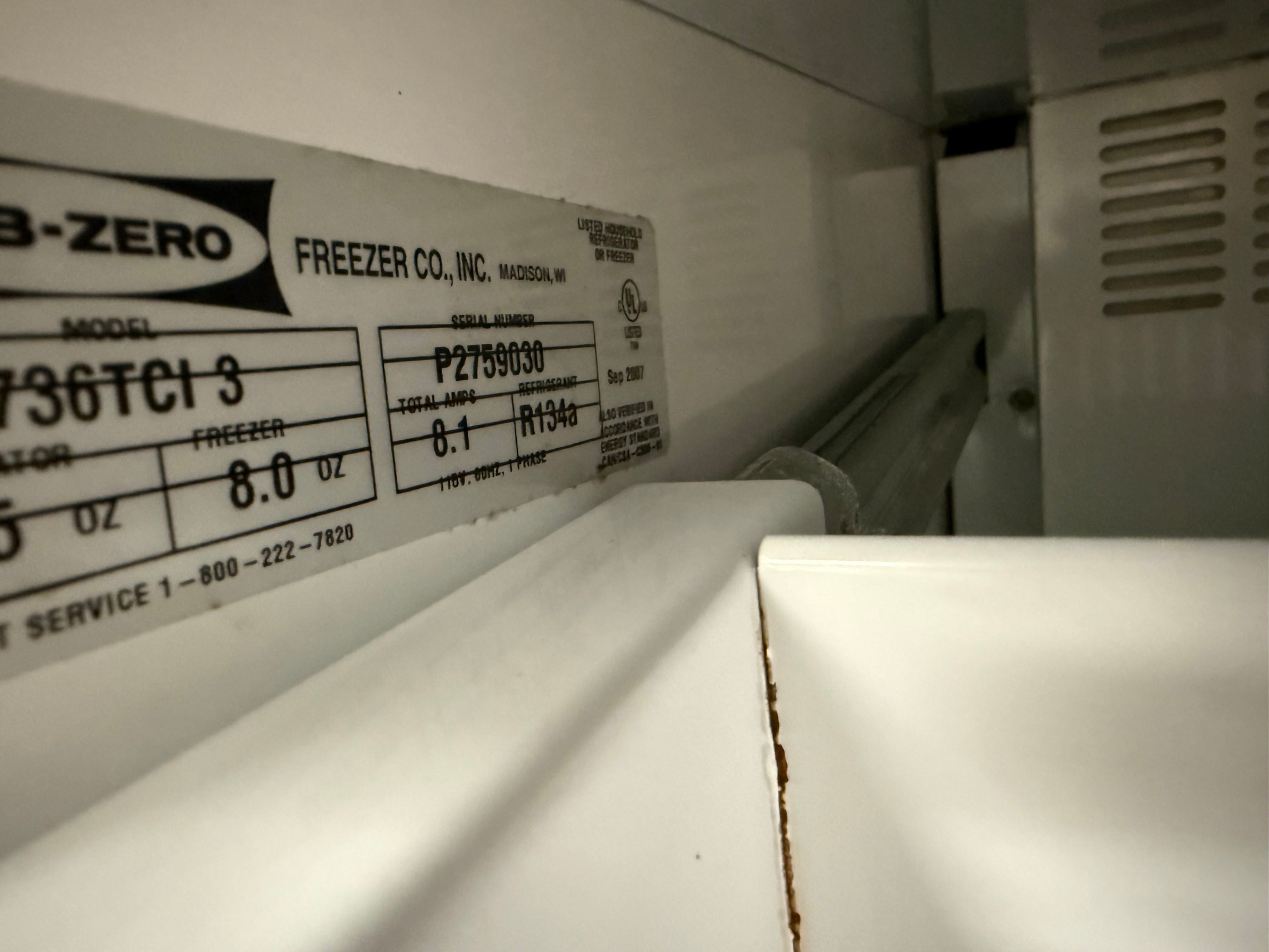 Close-up of a white refrigerator interior label showing the Frezer Co. model information for a freezer.