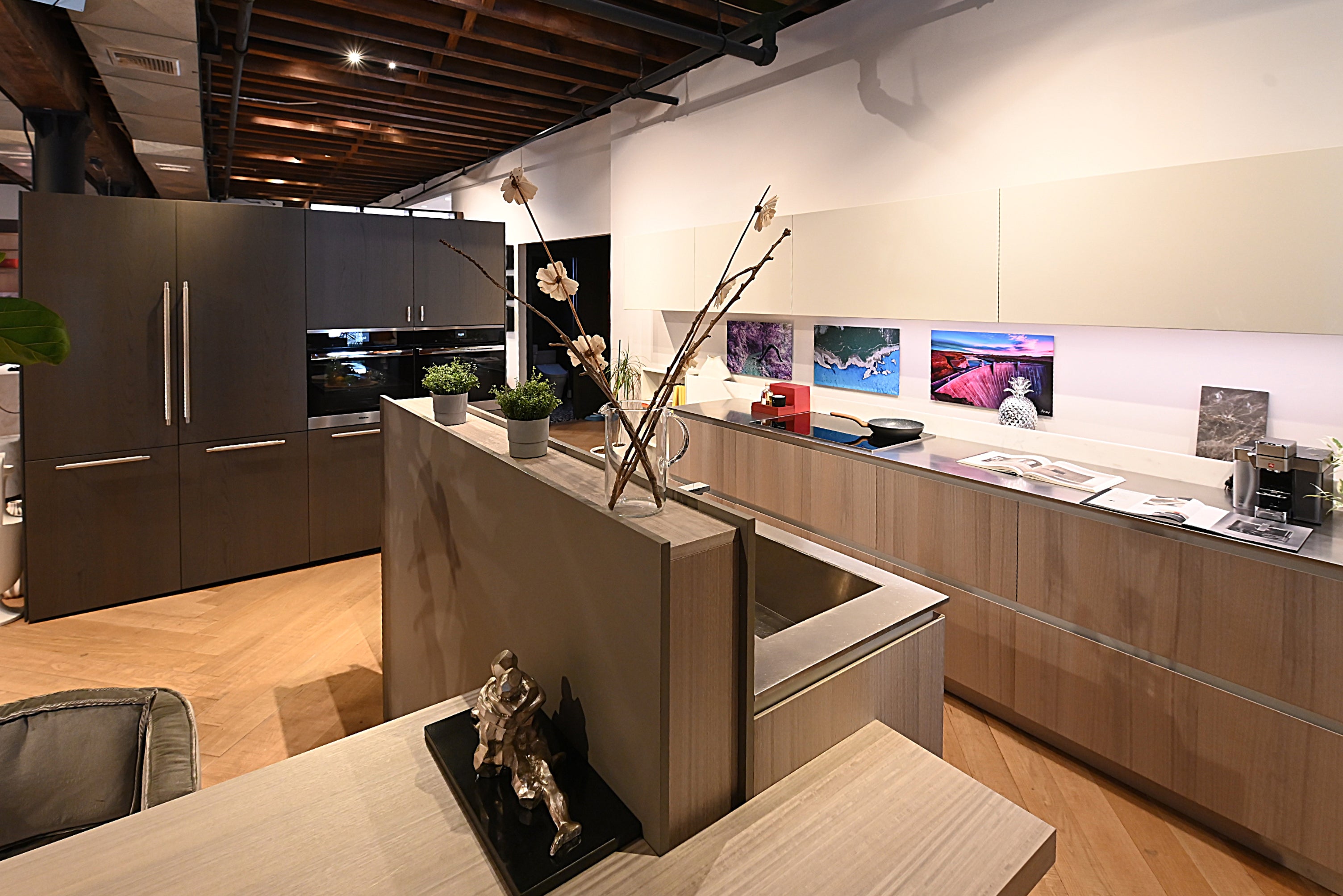 Copatlife modern open concept Italian kitchen featuring dark wood perimeter cabinets a minimalist gray island and integrated Miele appliances
