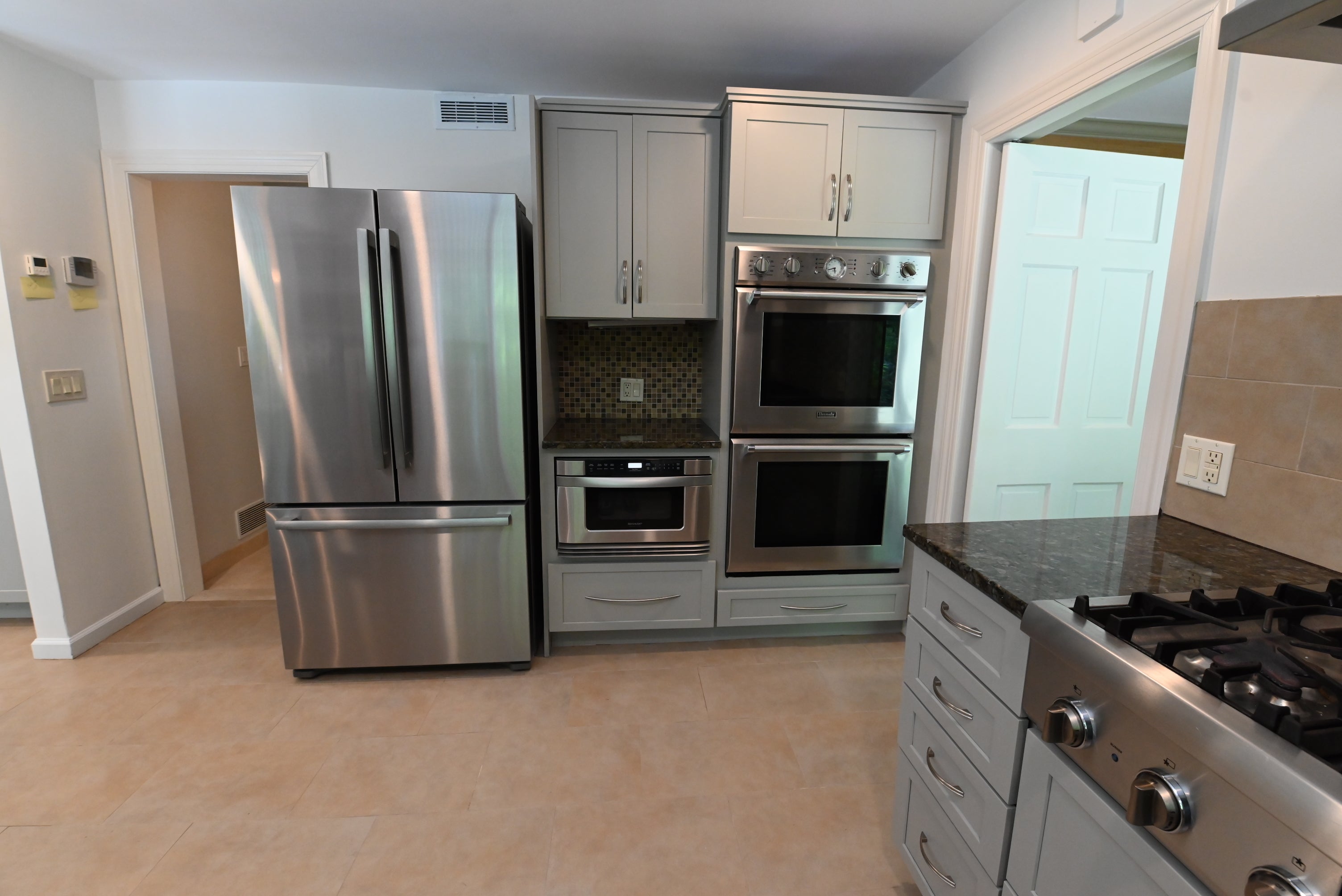 Complete estate reclaimed transitional kitchen layout showing built in refrigerator and range hood canopy