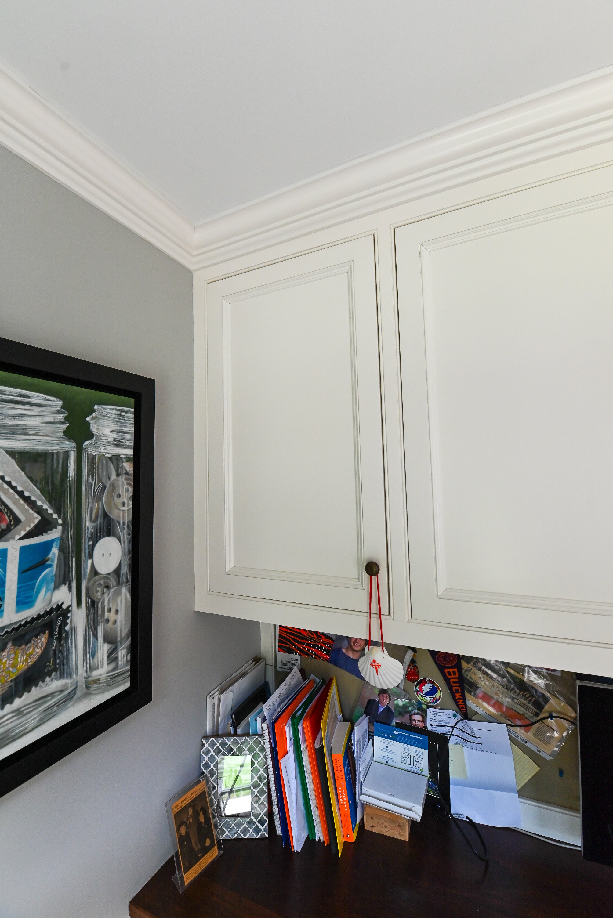 Transitional white built in home office desk system with a warm solid natural wood countertop and upper bookshelf display shelving