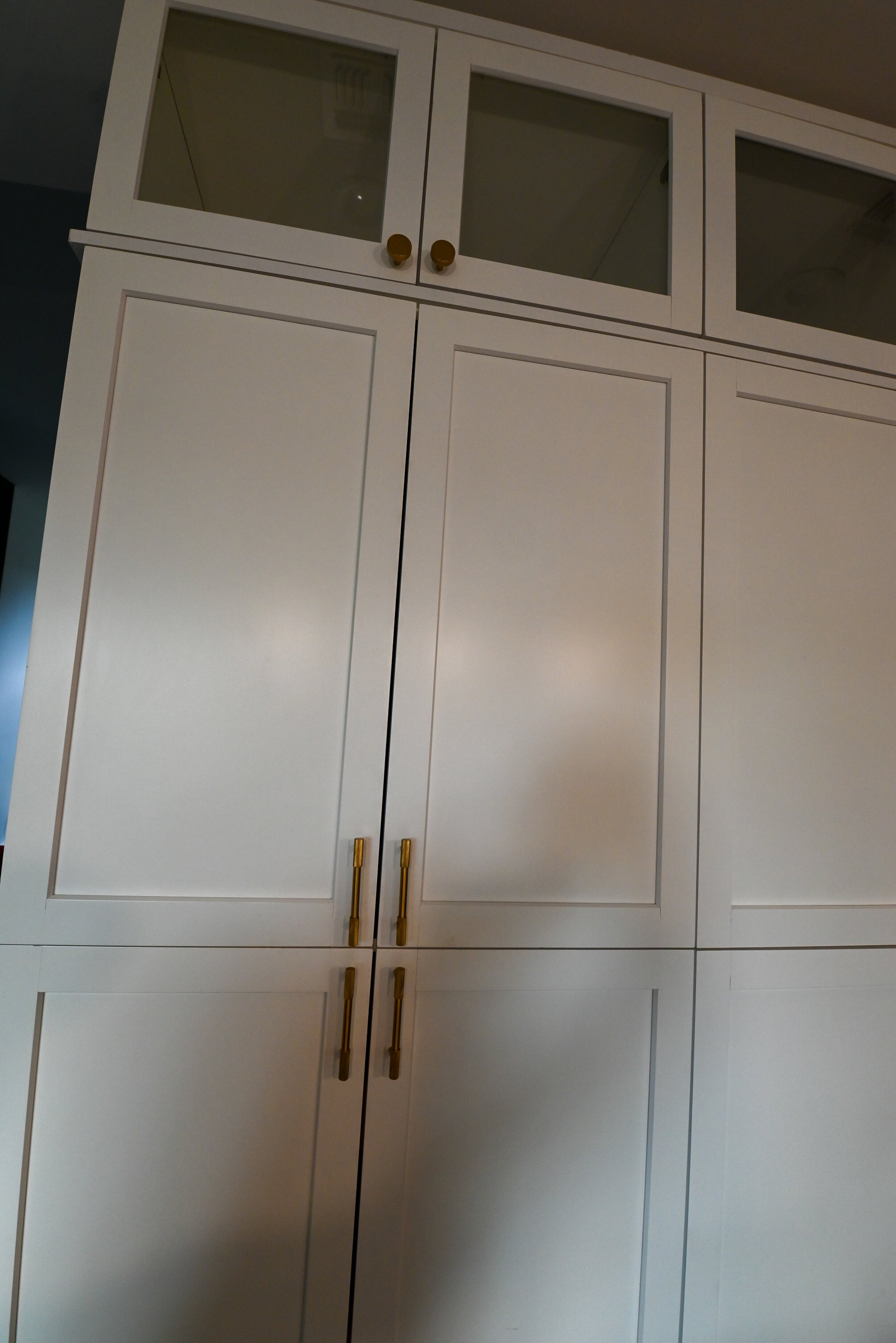 Full kitchen view of crisp white shaker cabinets with crown molding and integrated appliance wall towers