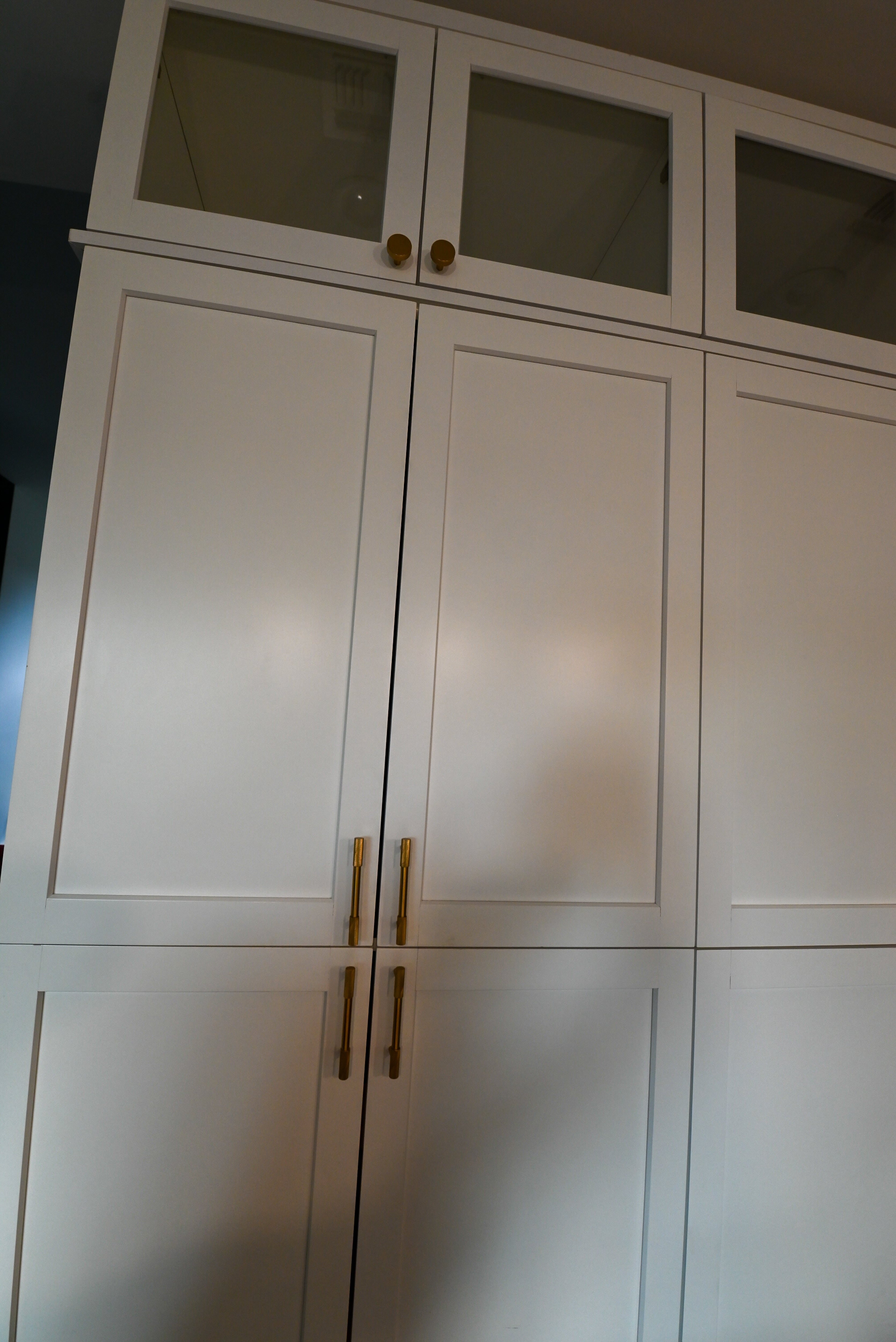 Full kitchen view of crisp white shaker cabinets with crown molding and integrated appliance wall towers
