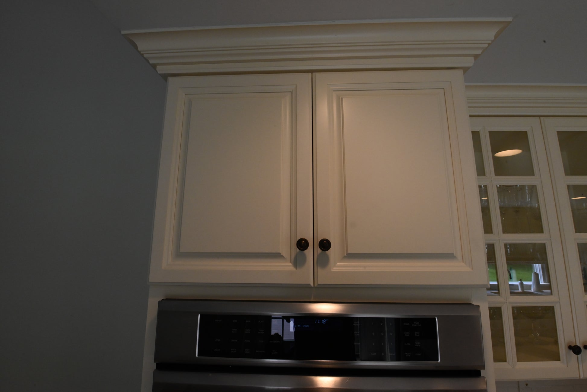 Close up view of the traditional light cream raised panel cabinet doors with decorative crown molding
