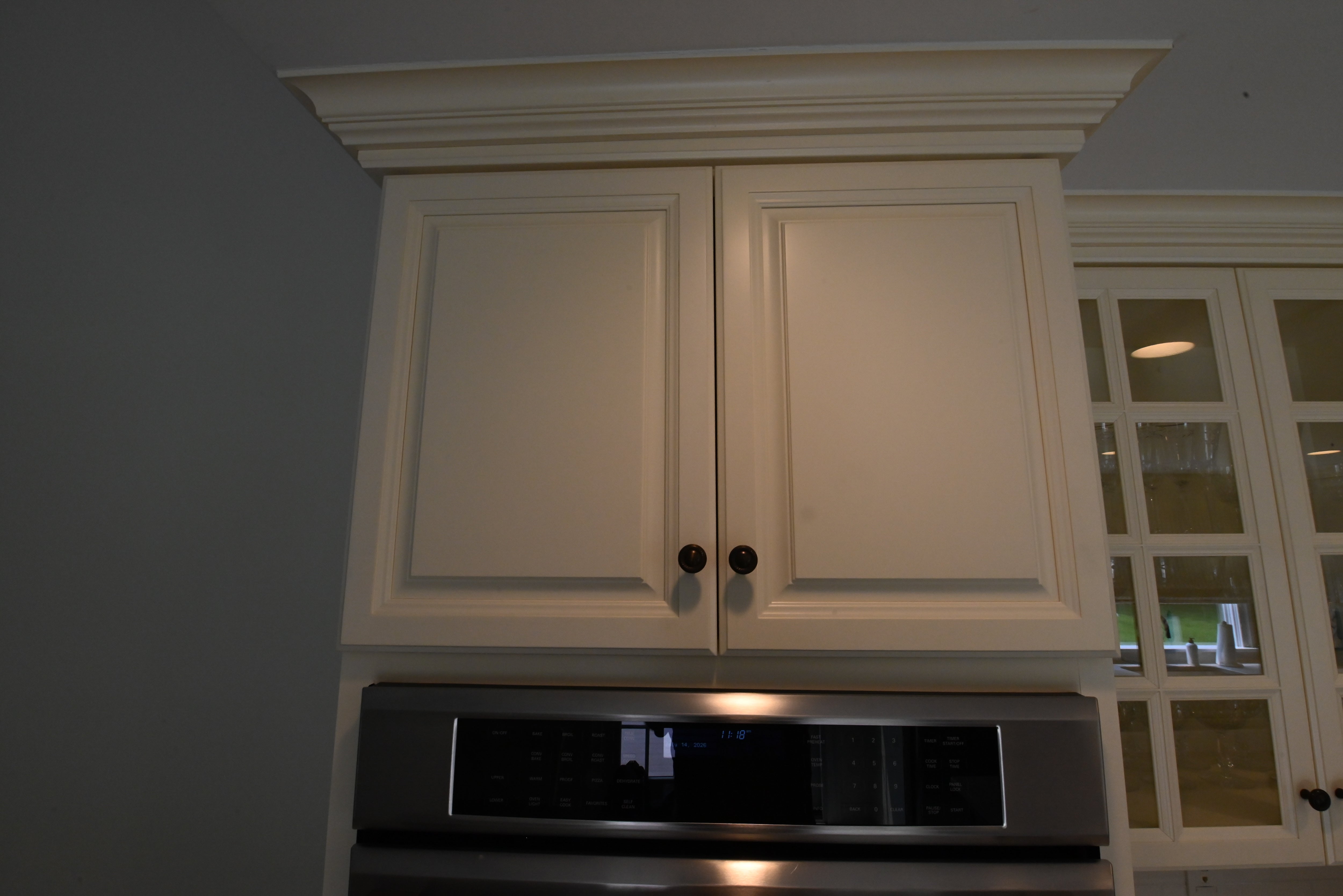 Close up view of the traditional light cream raised panel cabinet doors with decorative crown molding