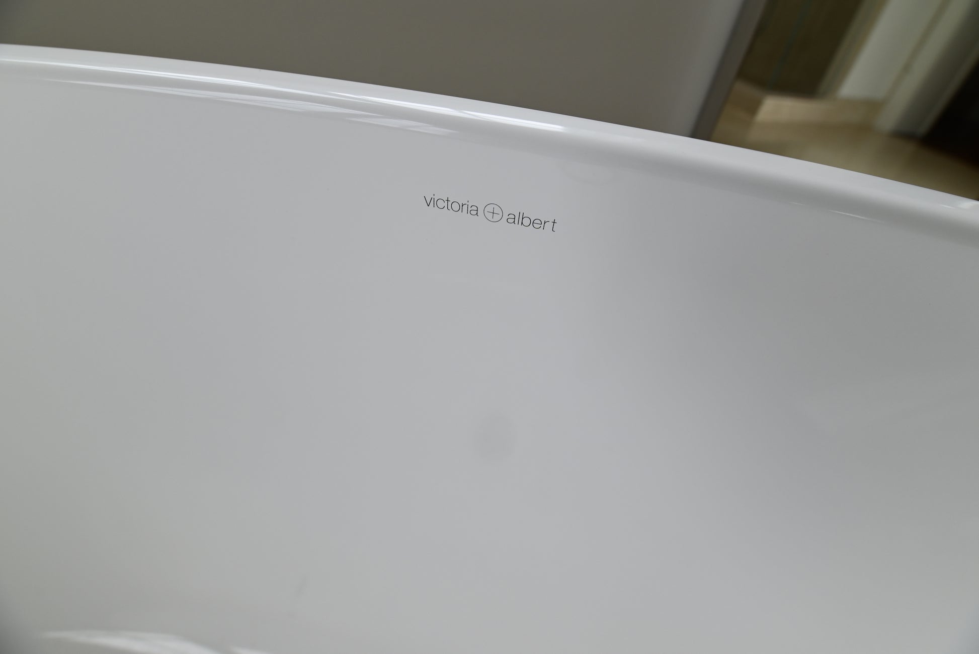 Close-up of a white freestanding bathtub corner with the Victoria Albert brand name printed in small gray text on the inner rim.