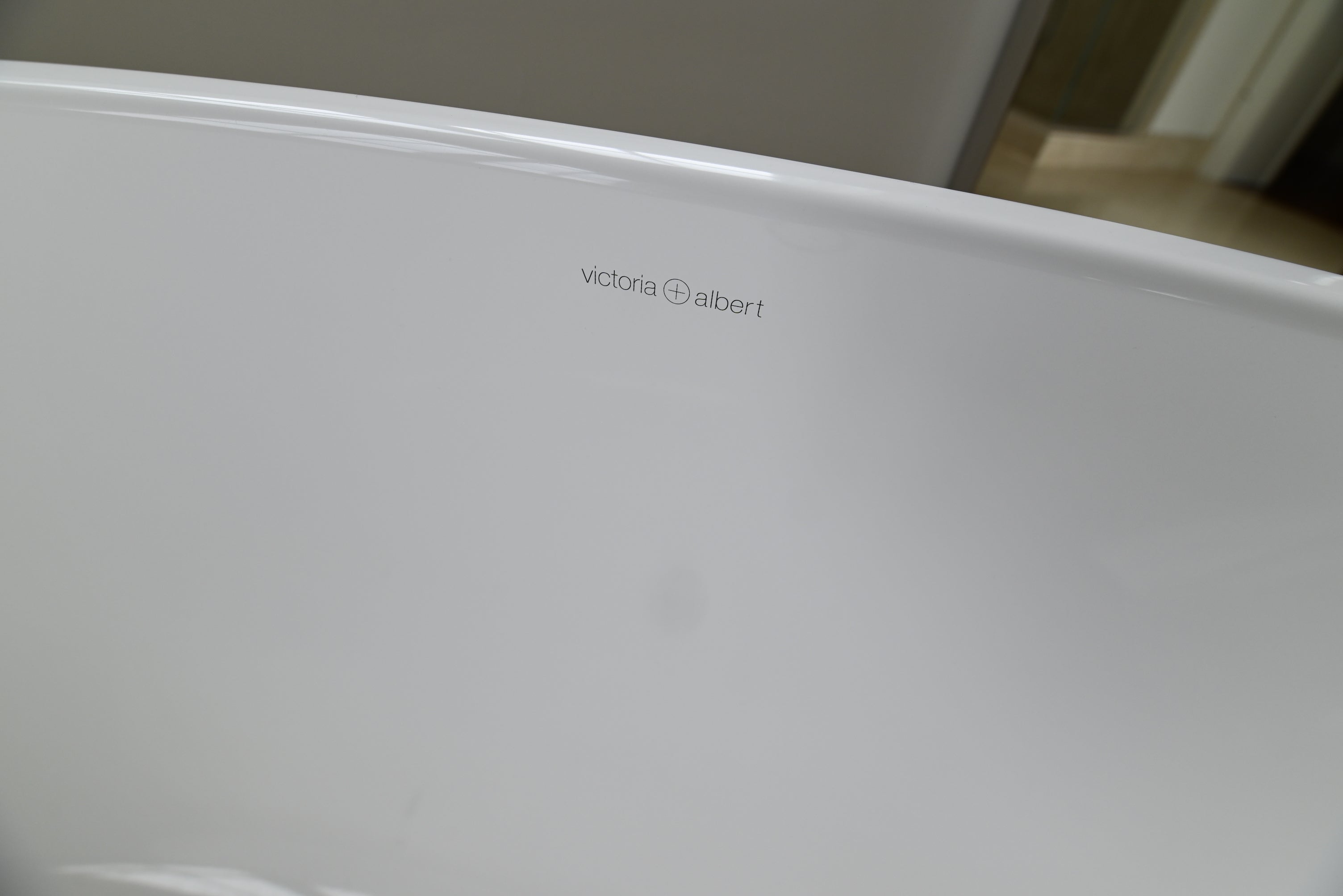 Close-up of a white freestanding bathtub corner with the Victoria Albert brand name printed in small gray text on the inner rim.