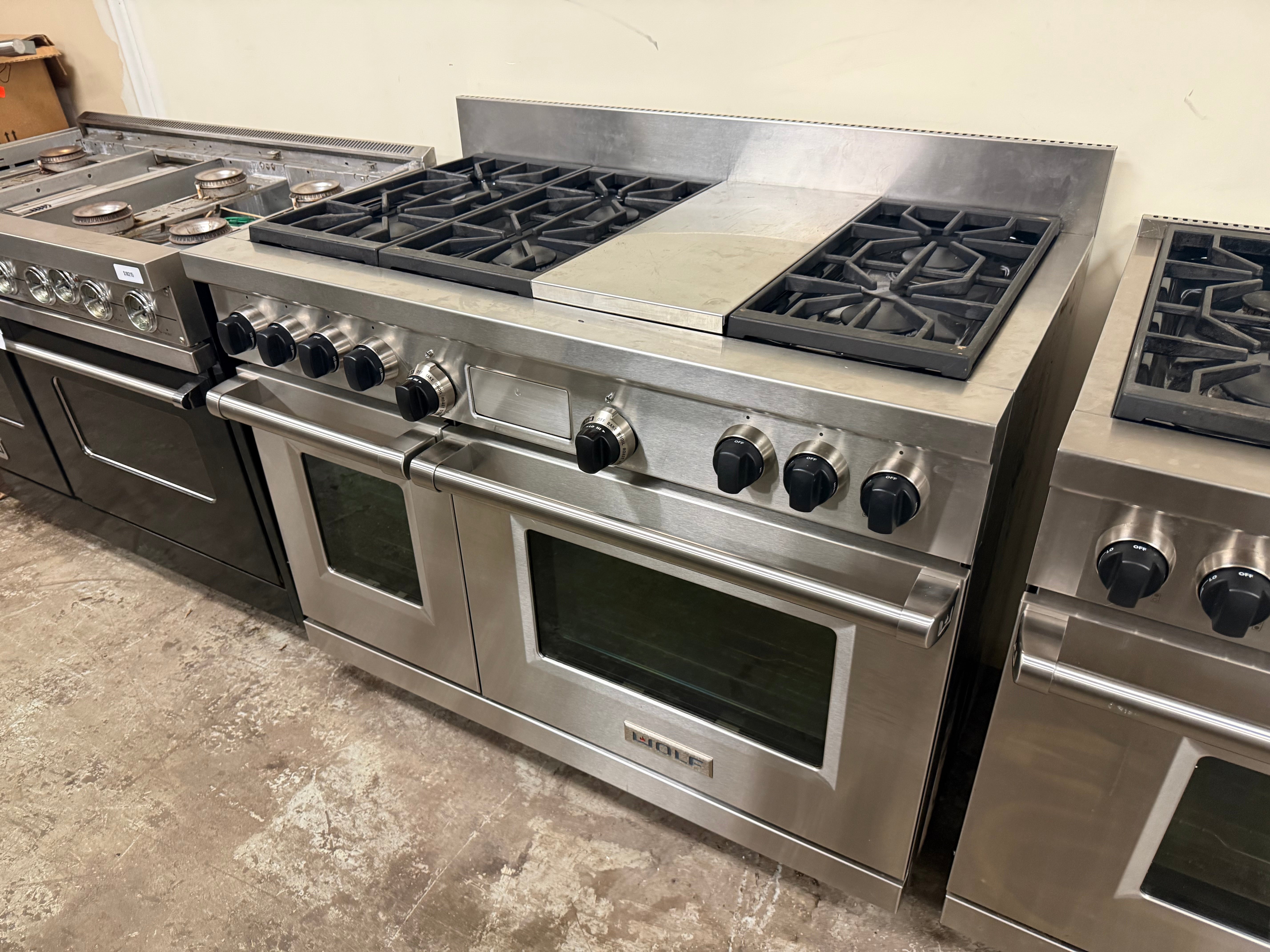 Pre owned Wolf 48 inch dual fuel range open doors showing dual electric oven cavities with cobalt blue porcelain interiors