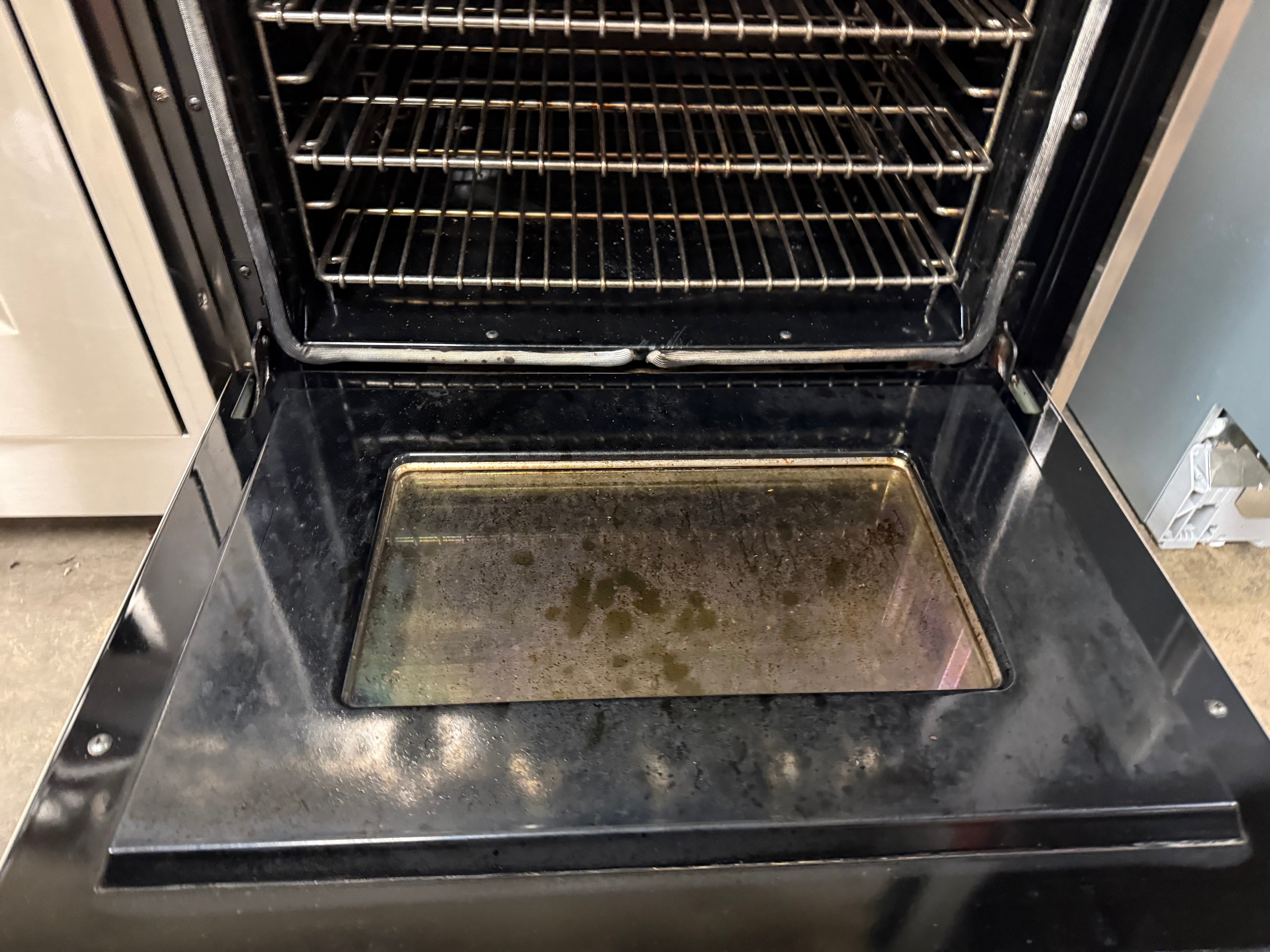 Oven with a baking tray inside, open door showing racks.