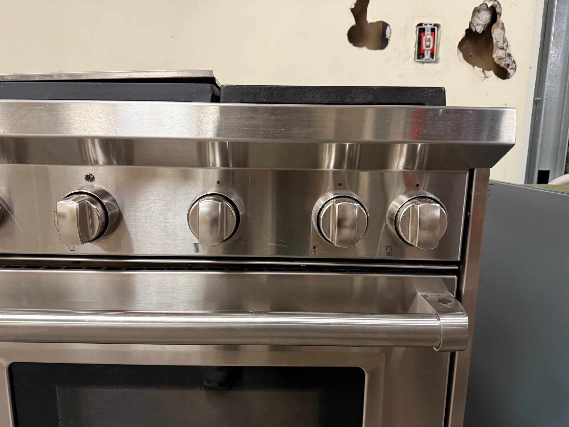 Close-up of the iconic Wolf control knobs against the brushed stainless steel control panel.