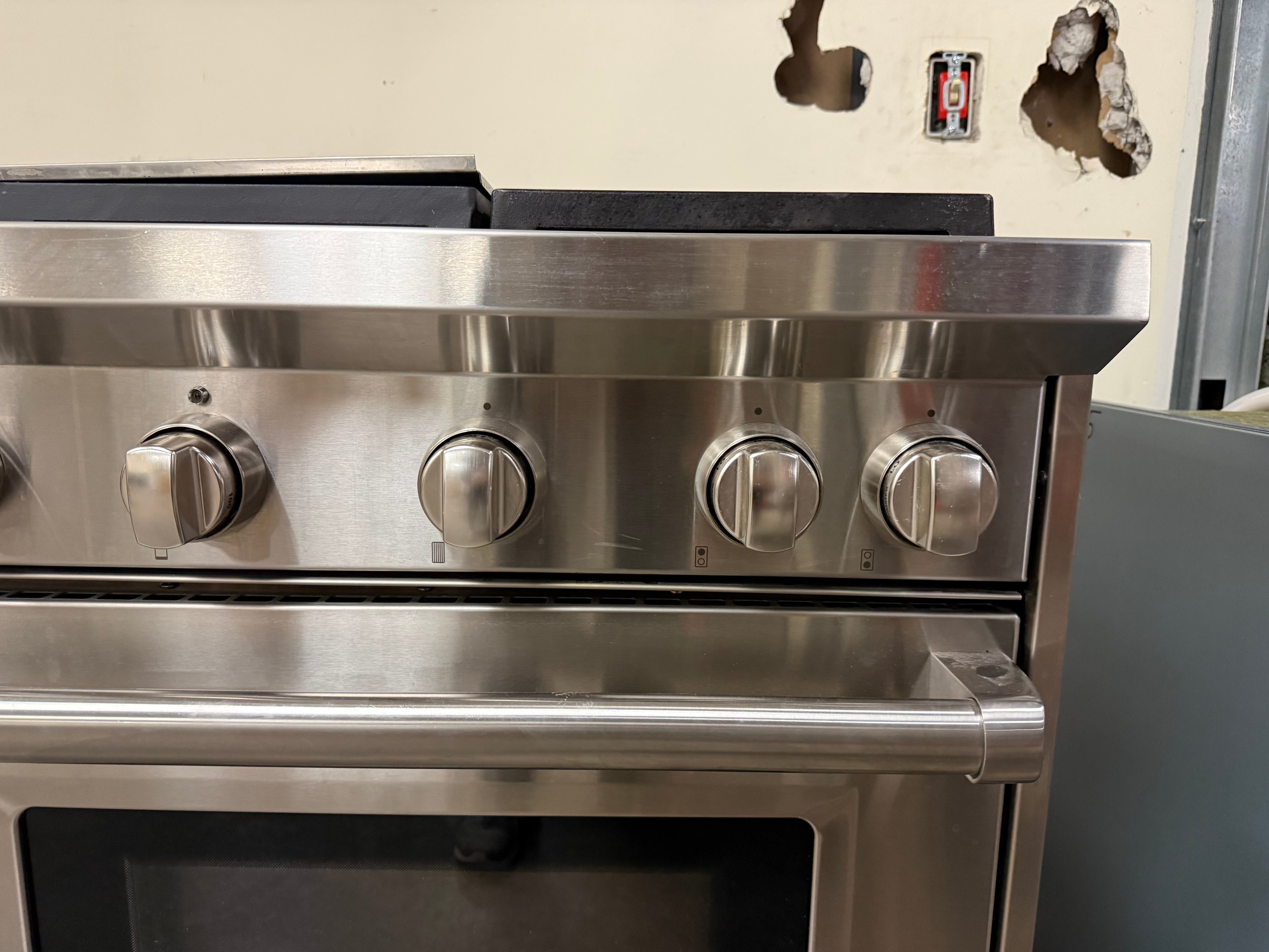 Close-up of the iconic Wolf control knobs against the brushed stainless steel control panel.