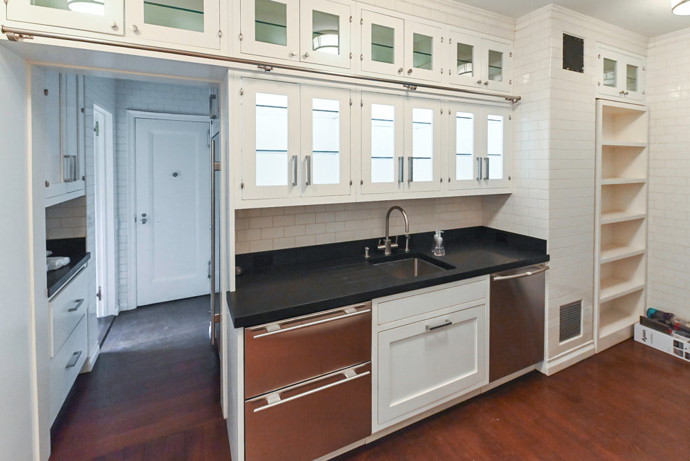 Modern kitchen with white cabinets, black countertops, and stainless steel appliances.
